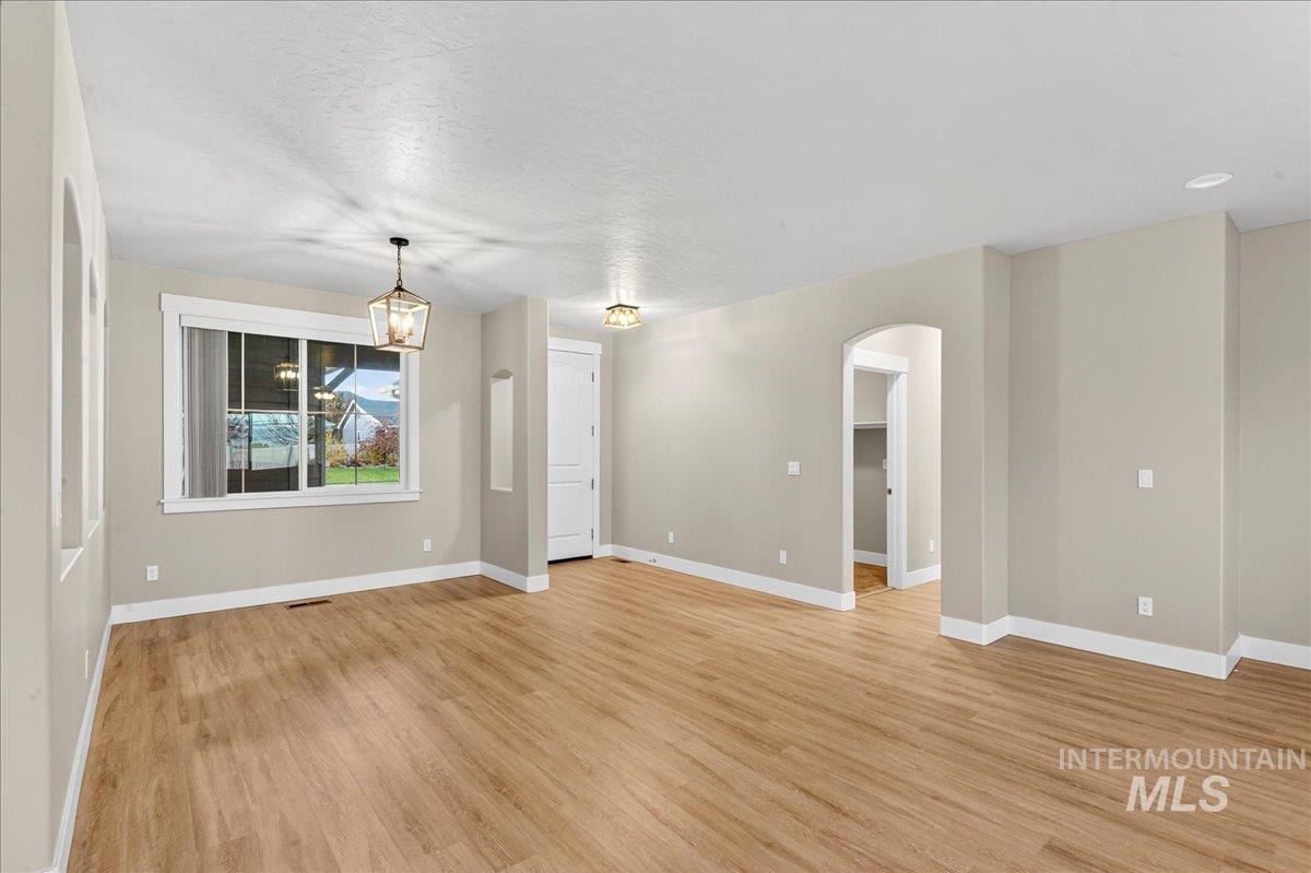 Spare room featuring light wood-style floors, arched walkways, and a textured ceiling
