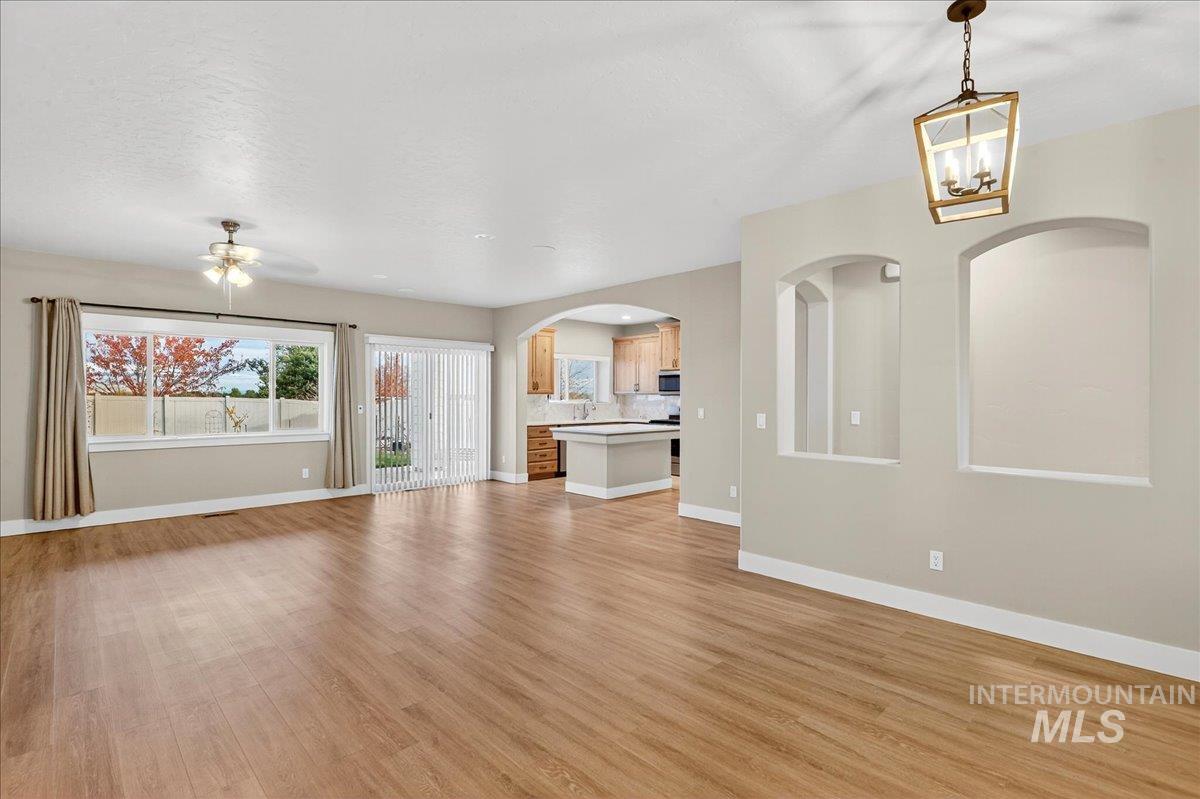 Unfurnished living room with arched walkways and light wood-type flooring
