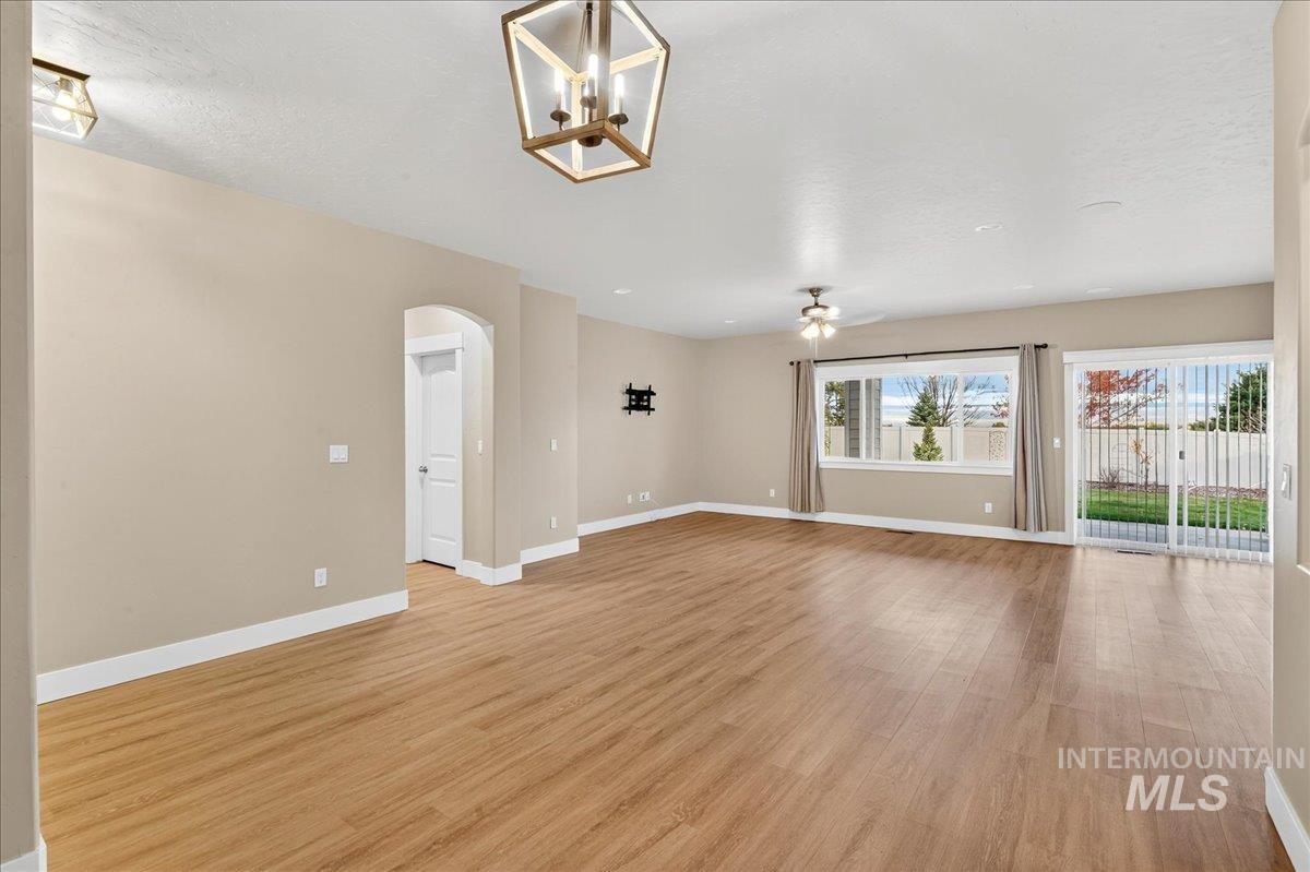 Unfurnished living room featuring arched walkways, ceiling fan, and light wood-style floors