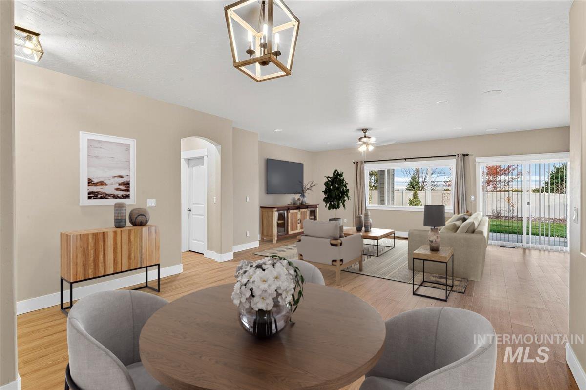 Dining space featuring arched walkways, light wood-style flooring, and a ceiling fan