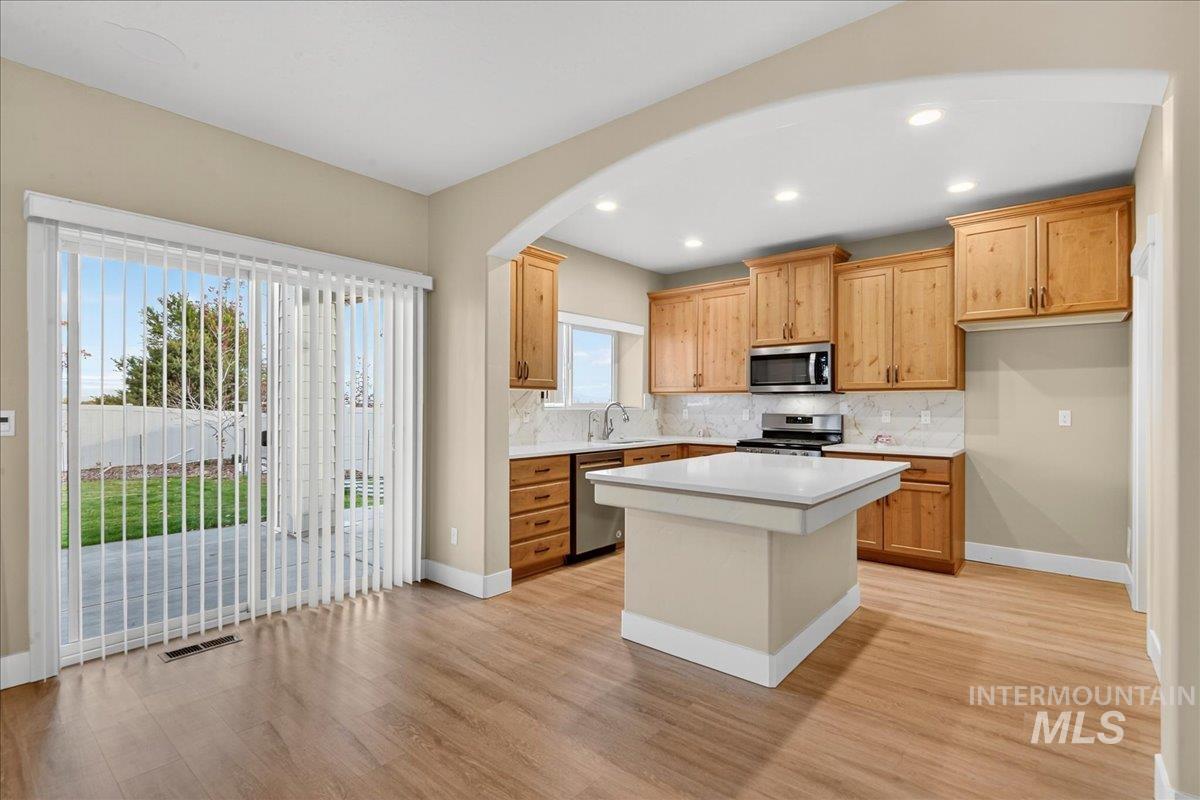 Kitchen featuring tasteful backsplash, a center island, light wood-style flooring, recessed lighting, and stainless steel appliances