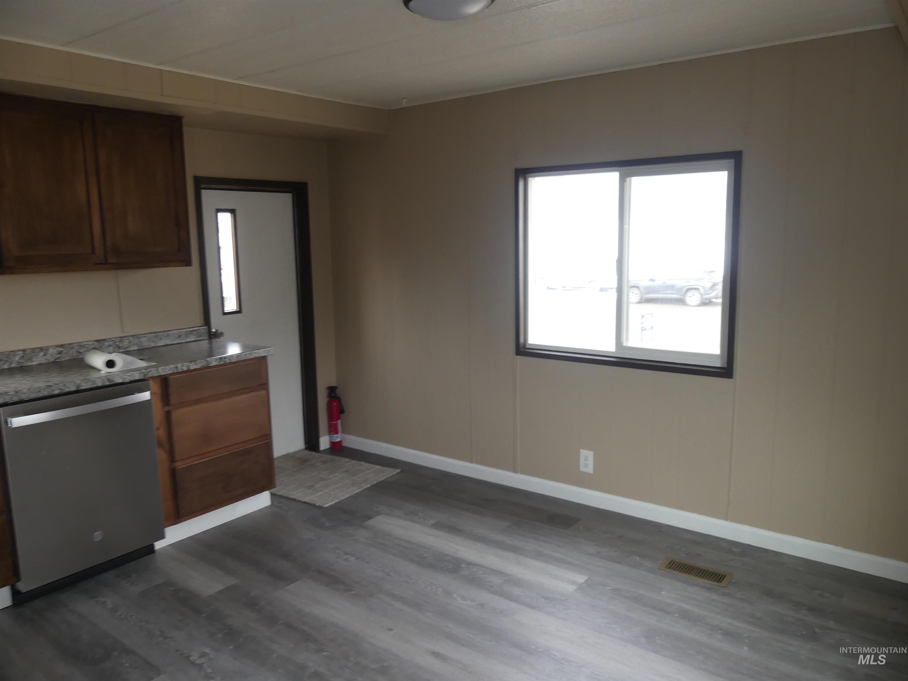 Kitchen with dishwasher, healthy amount of natural light, dark wood finished floors, and dark brown cabinets