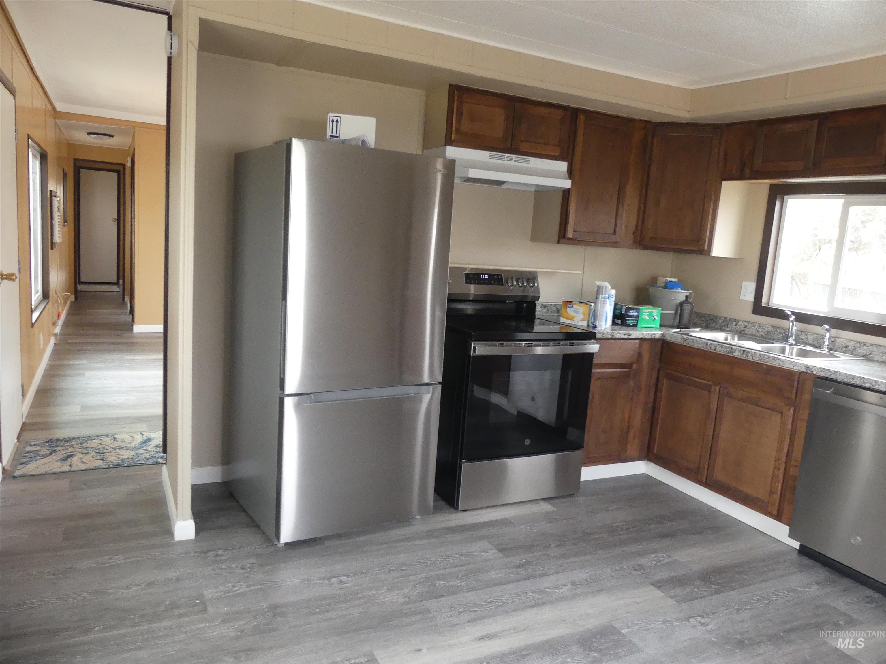Kitchen with stainless steel appliances, dark wood-type flooring, under cabinet range hood, and crown molding