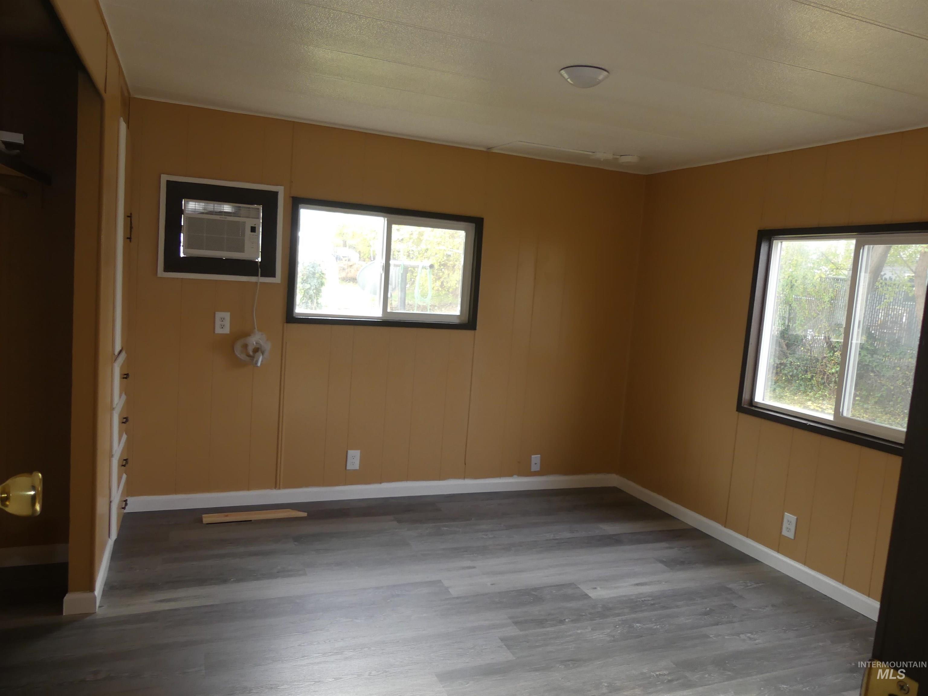 Empty room featuring wood finished floors, healthy amount of natural light, wood walls, and a wall mounted air conditioner