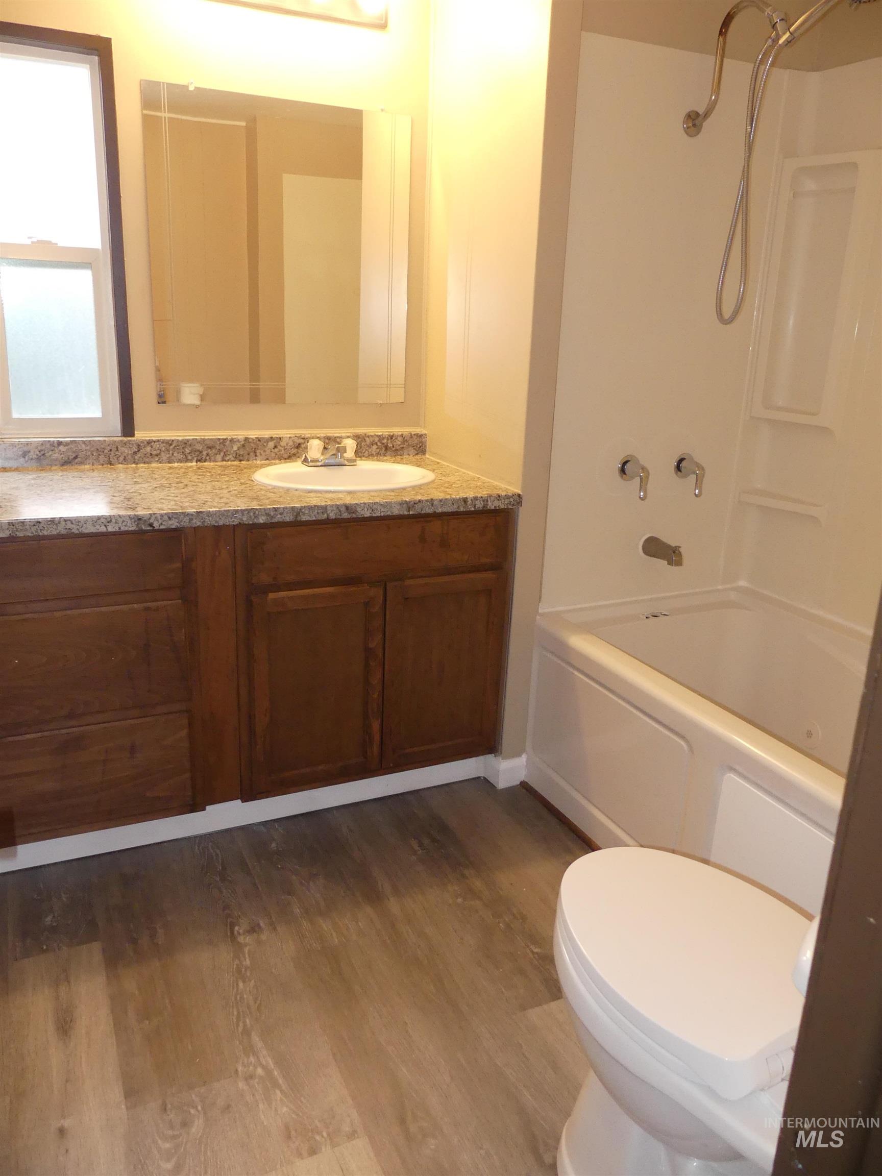 Bathroom with tub / shower combination, vanity, and dark wood-type flooring