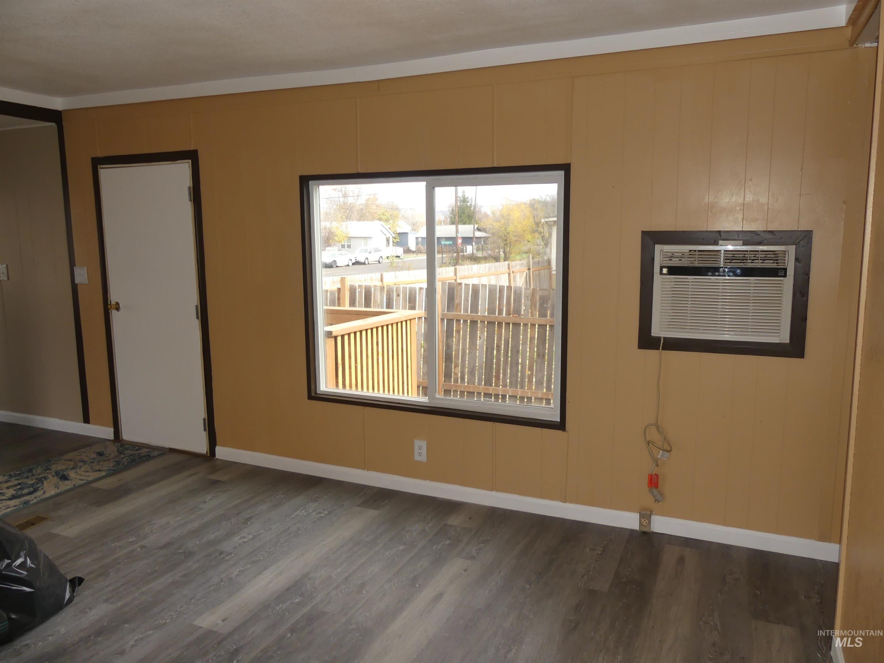 Unfurnished bedroom with dark wood-style floors and a wall unit AC