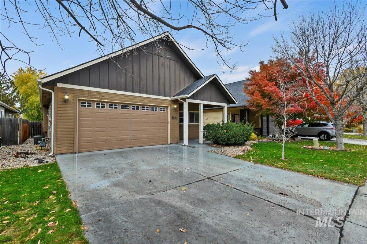 View of front of home with a front yard, driveway, an attached garage, and board and batten siding