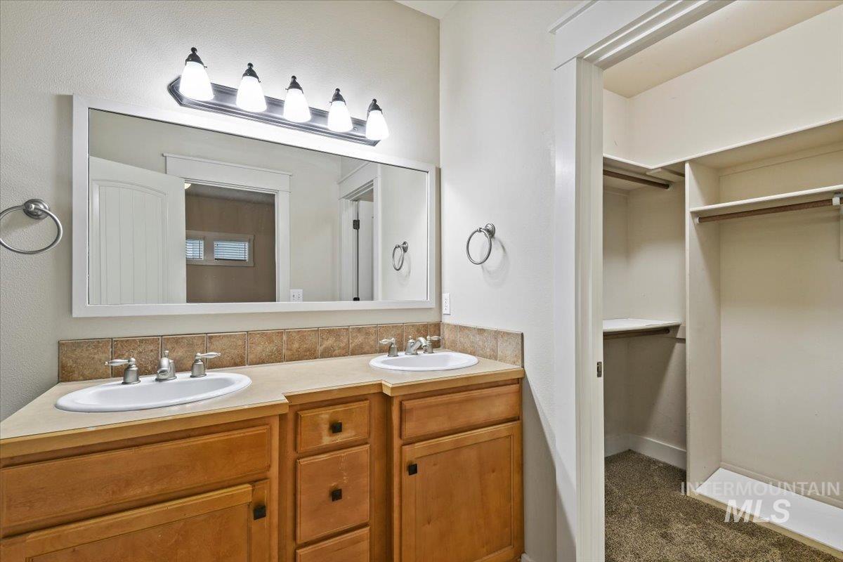Full bath with double vanity and a walk in closet