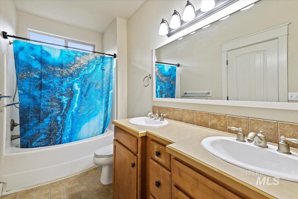 Full bathroom with shower / bath combination with curtain, double vanity, and decorative backsplash