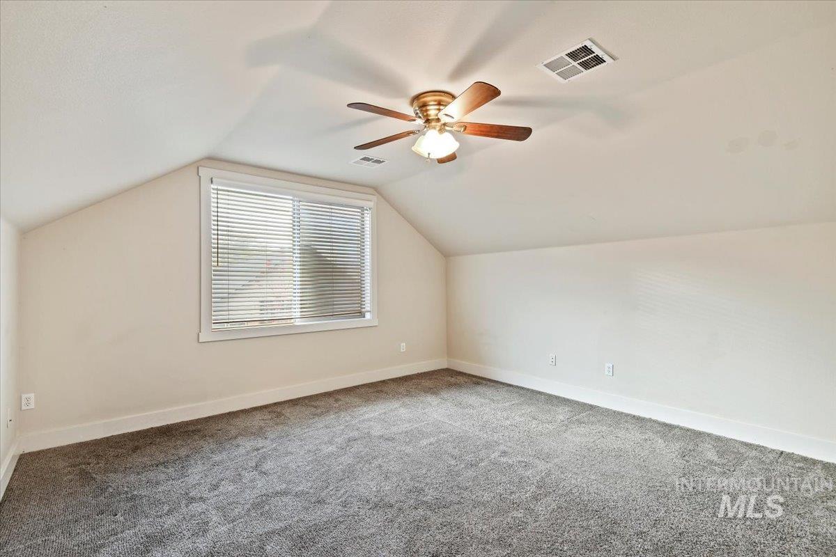 Additional living space featuring lofted ceiling, carpet, and ceiling fan
