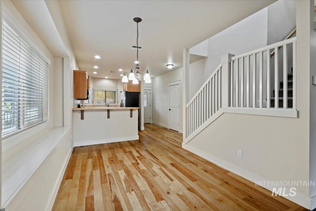 Kitchen featuring light wood-style floors, a breakfast bar area, light countertops, a peninsula, and hanging light fixtures