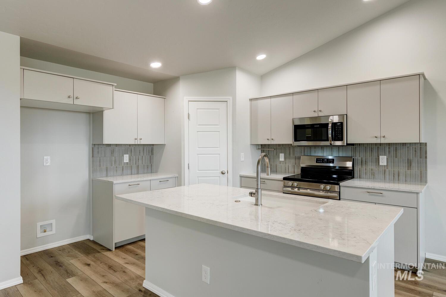 Kitchen with stainless steel appliances, light stone countertops, light wood-style floors, tasteful backsplash, and recessed lighting