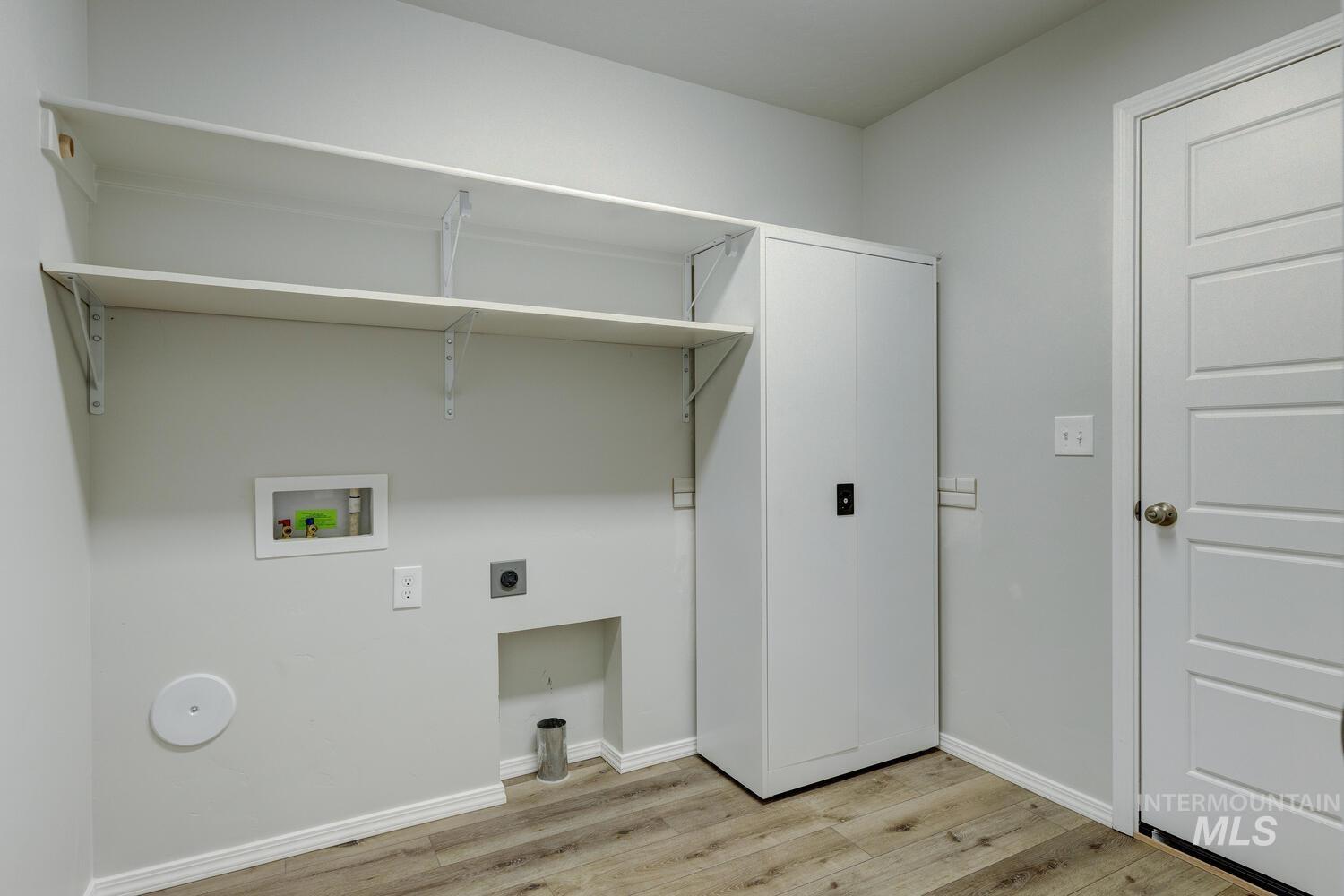 Laundry area with light wood-style floors, hookup for an electric dryer, and washer hookup