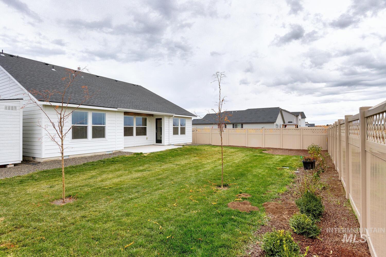 Rear view of property featuring a patio, a fenced backyard, and roof with shingles