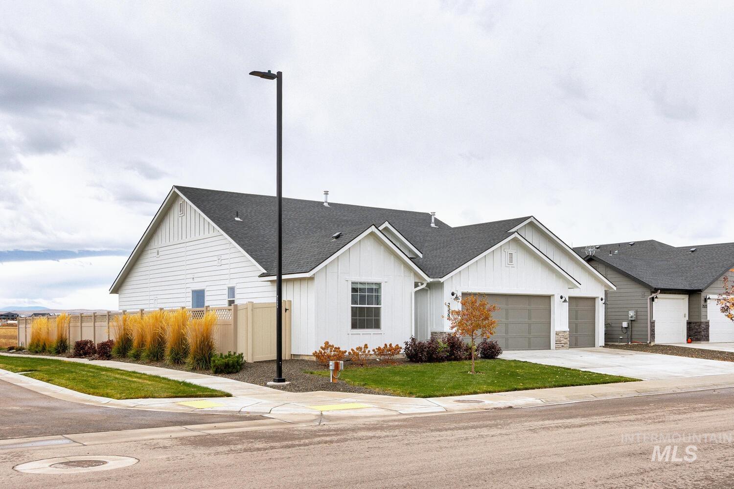 View of front of home with board and batten siding, a shingled roof, concrete driveway, and an attached garage