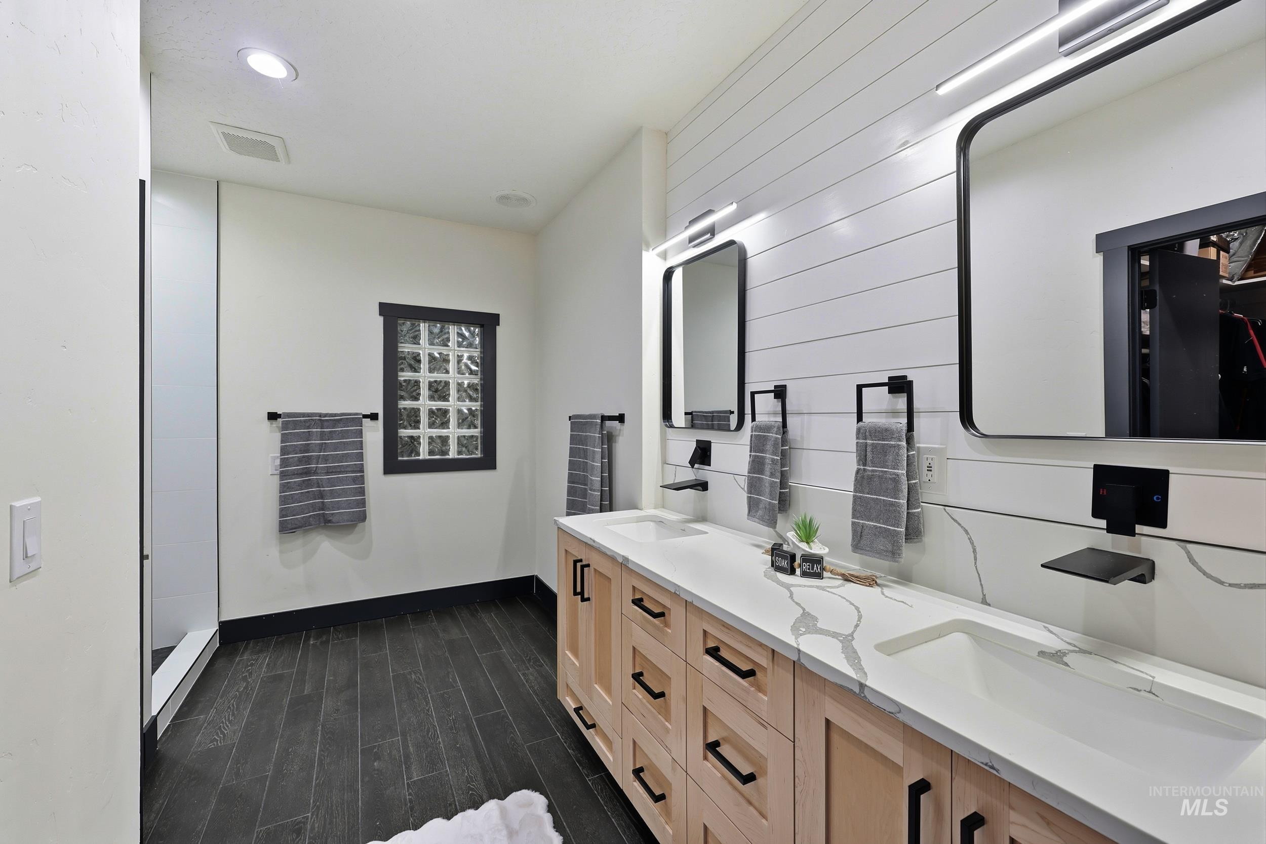 Bathroom with double vanity, dark wood finished floors, and recessed lighting