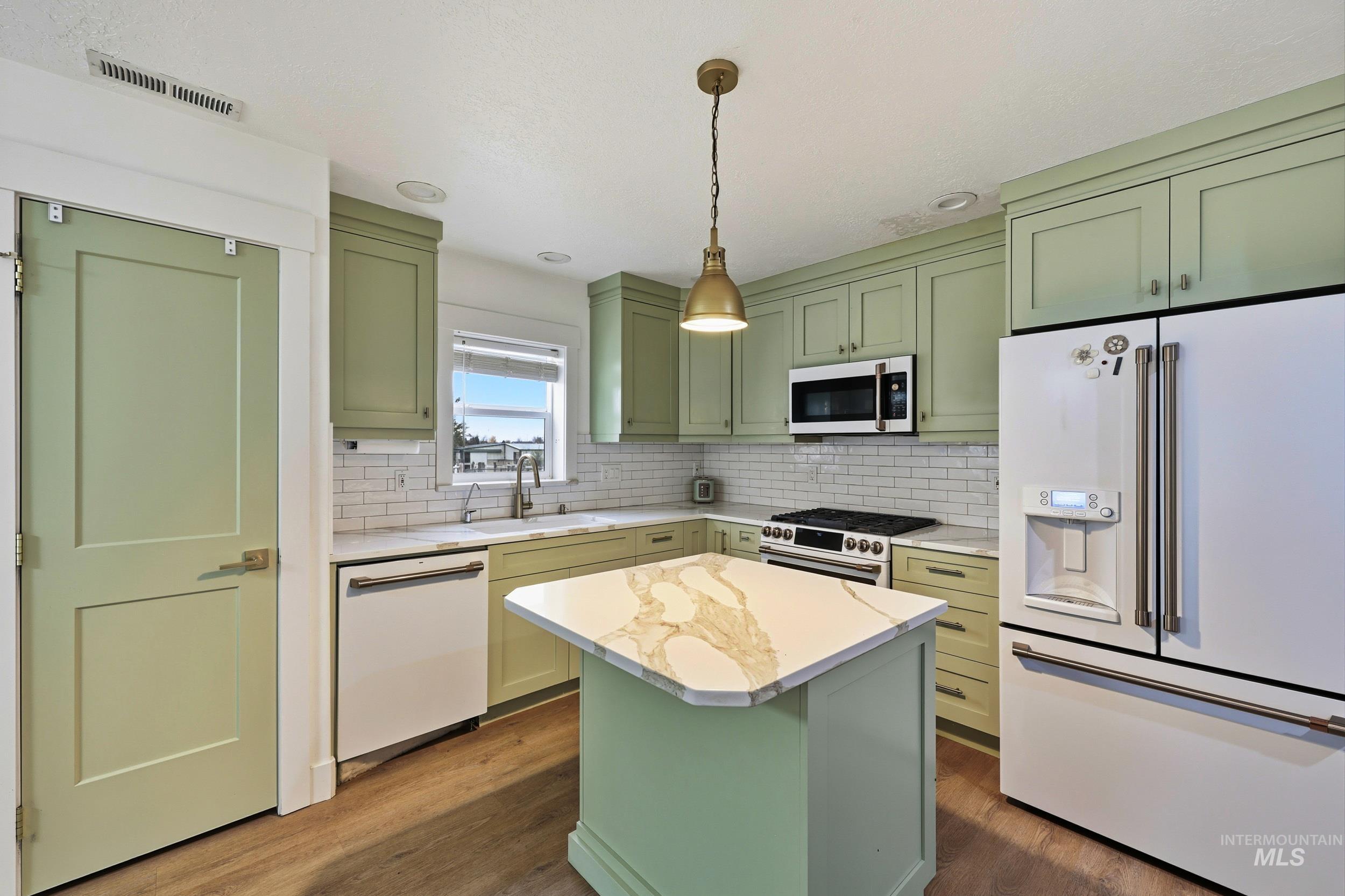 Kitchen featuring green cabinets, premium appliances, pendant lighting, dark wood-style flooring, and recessed lighting