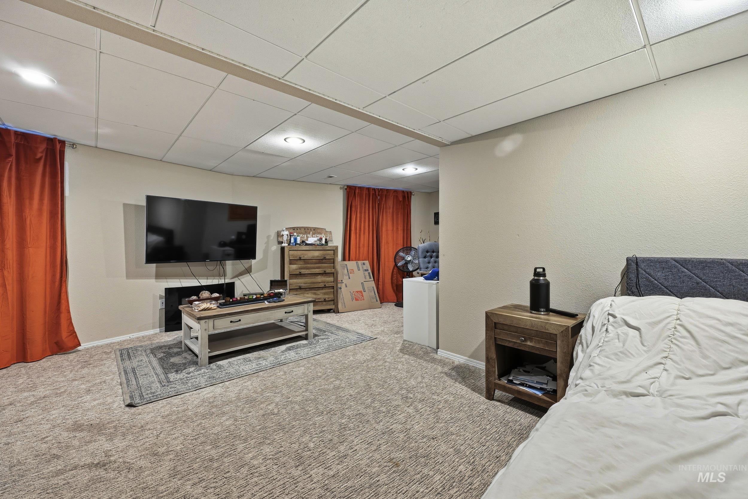 Carpeted bedroom featuring a paneled ceiling and baseboards