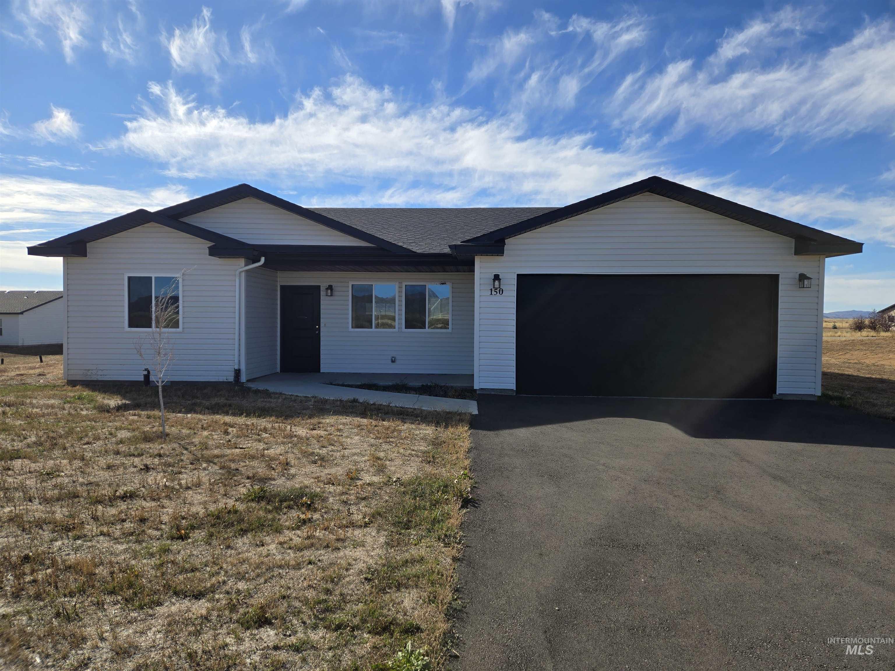 Single story home featuring driveway, an attached garage, a front lawn, and roof with shingles