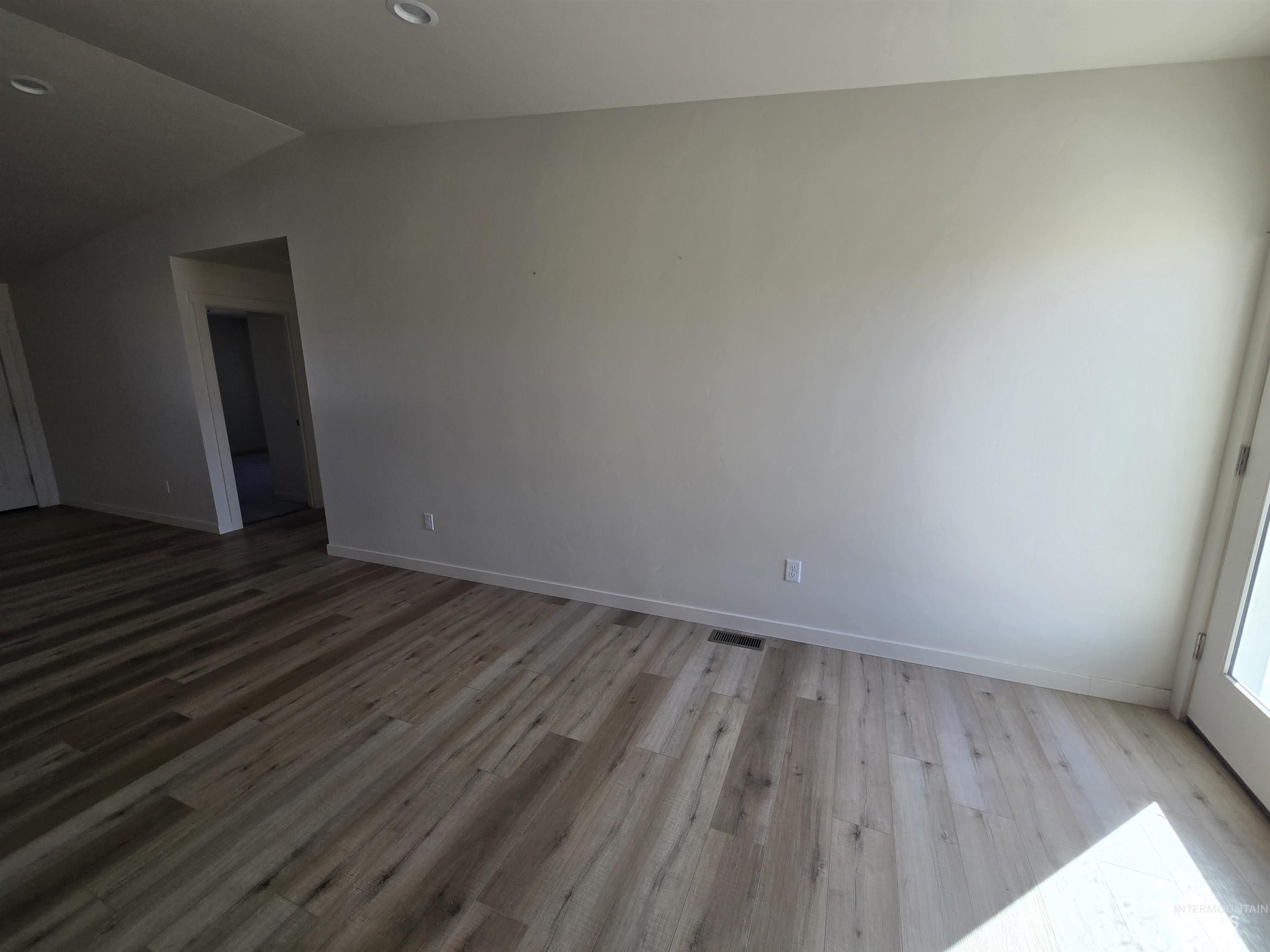 Spare room featuring light wood-type flooring, vaulted ceiling, and recessed lighting