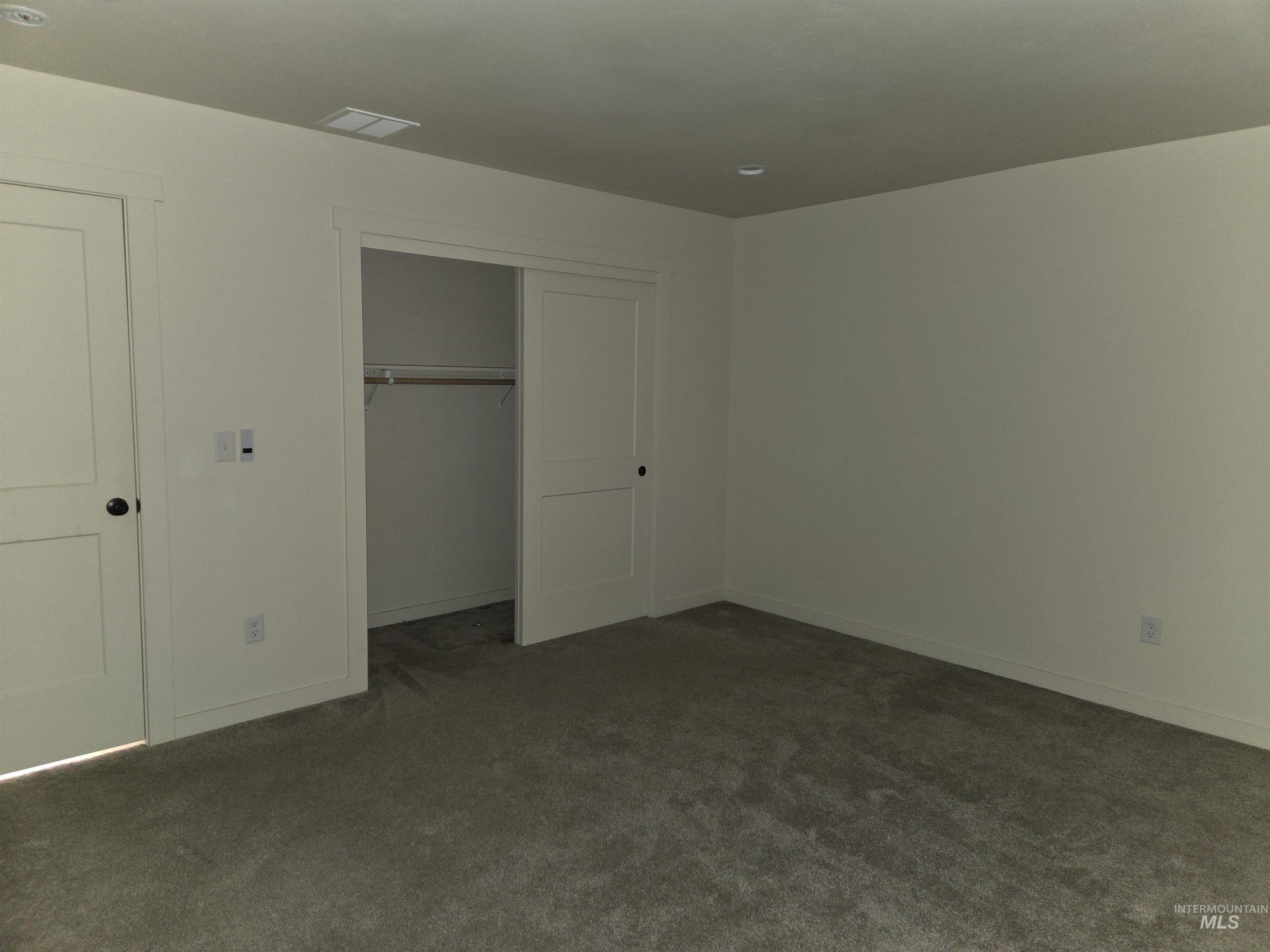 Unfurnished bedroom featuring dark colored carpet and a closet