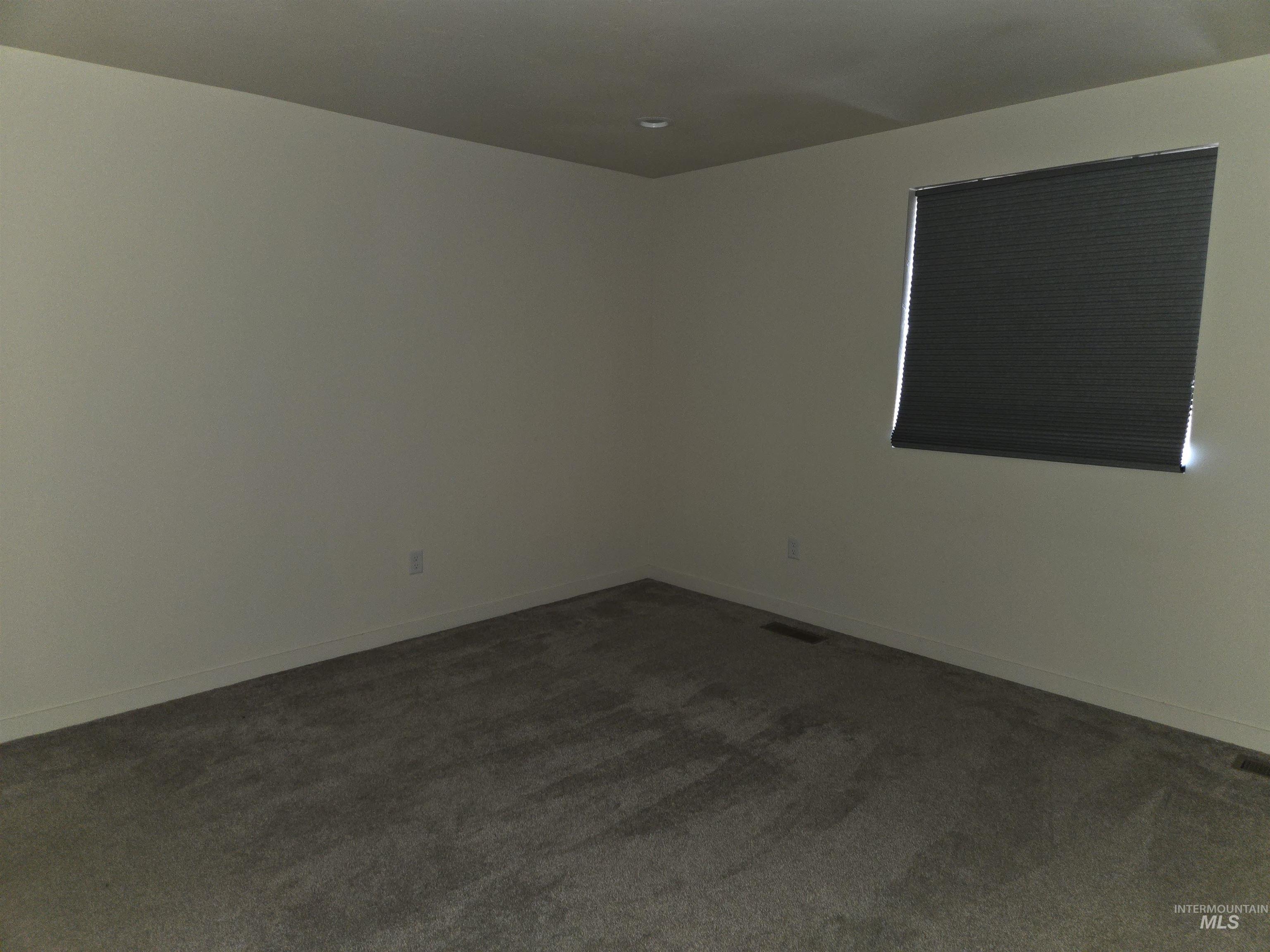 Empty room with dark carpet and baseboards