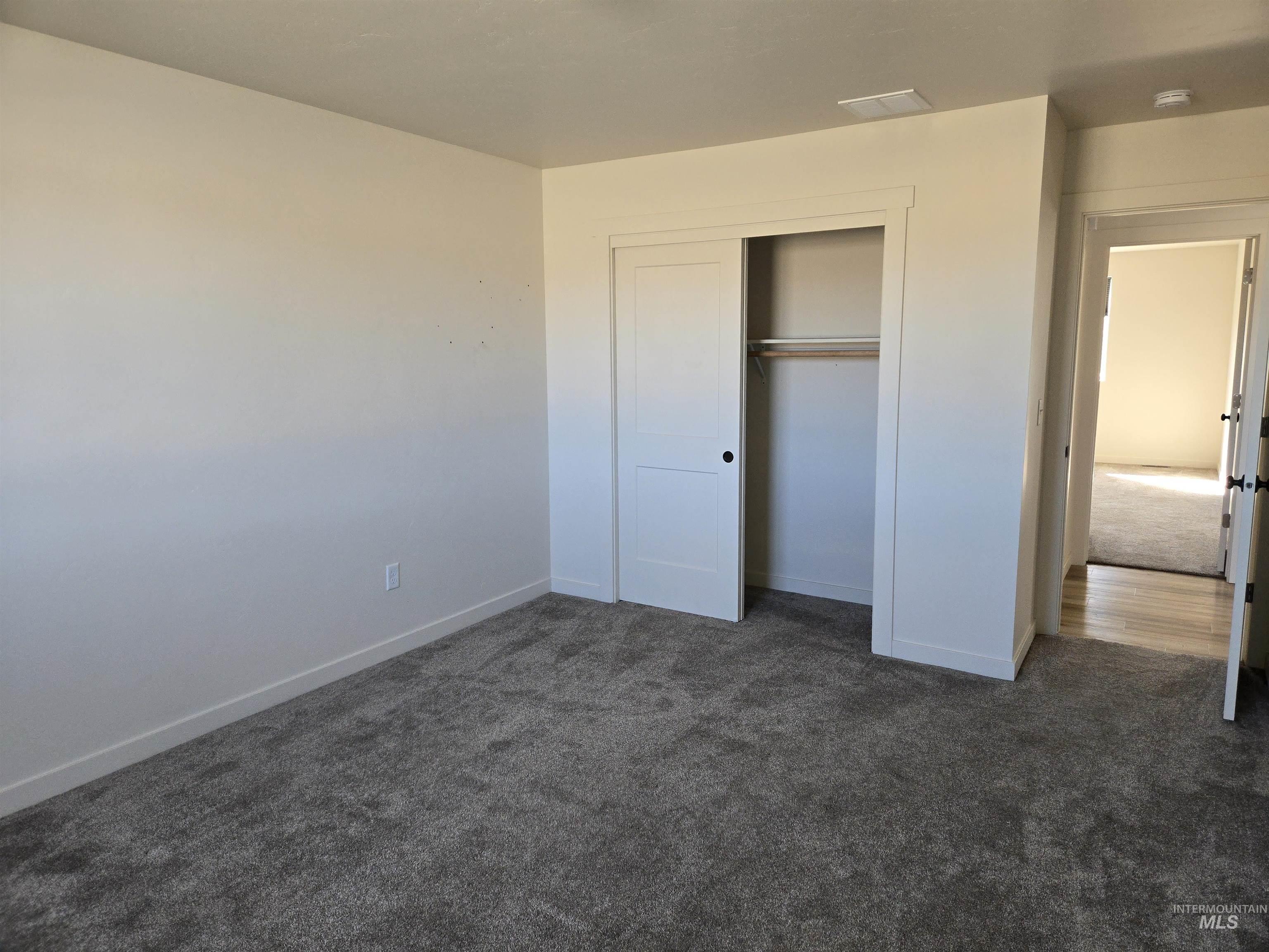 Unfurnished bedroom featuring dark colored carpet and a closet