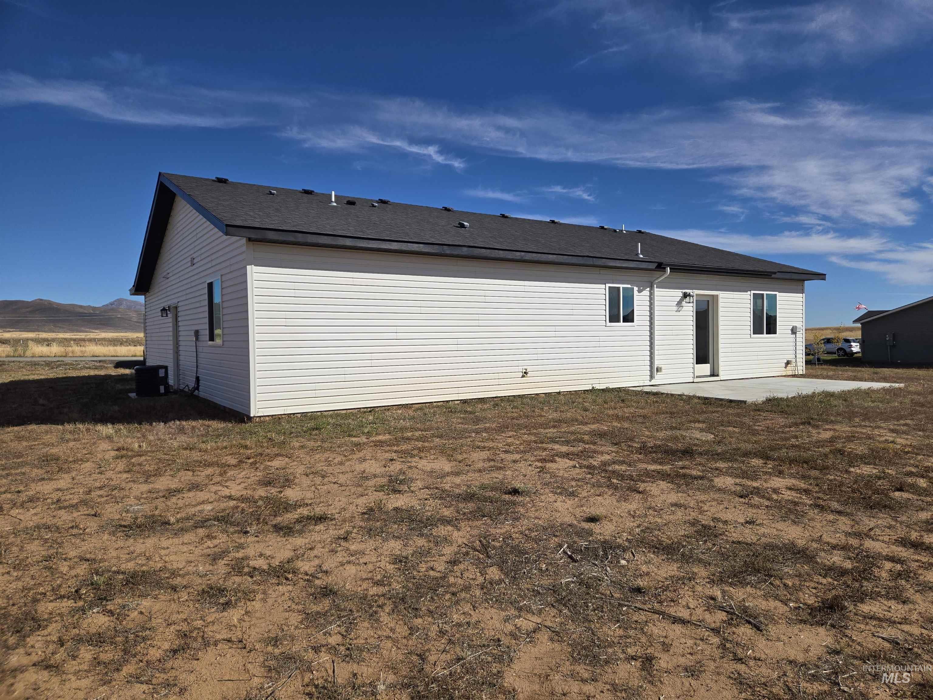 Back of property with a patio and roof with shingles