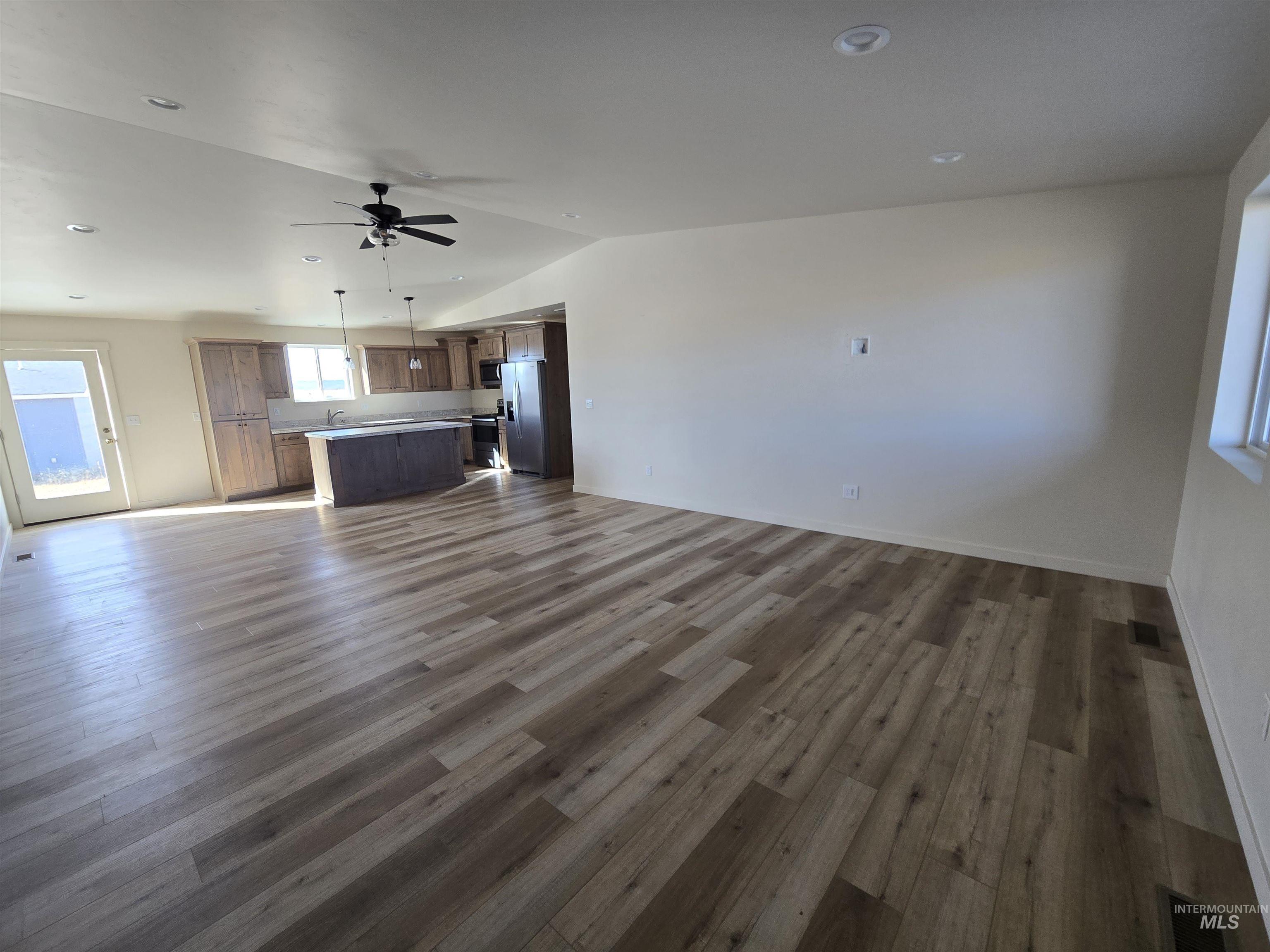 Unfurnished living room with dark wood-style floors, vaulted ceiling, ceiling fan, and recessed lighting