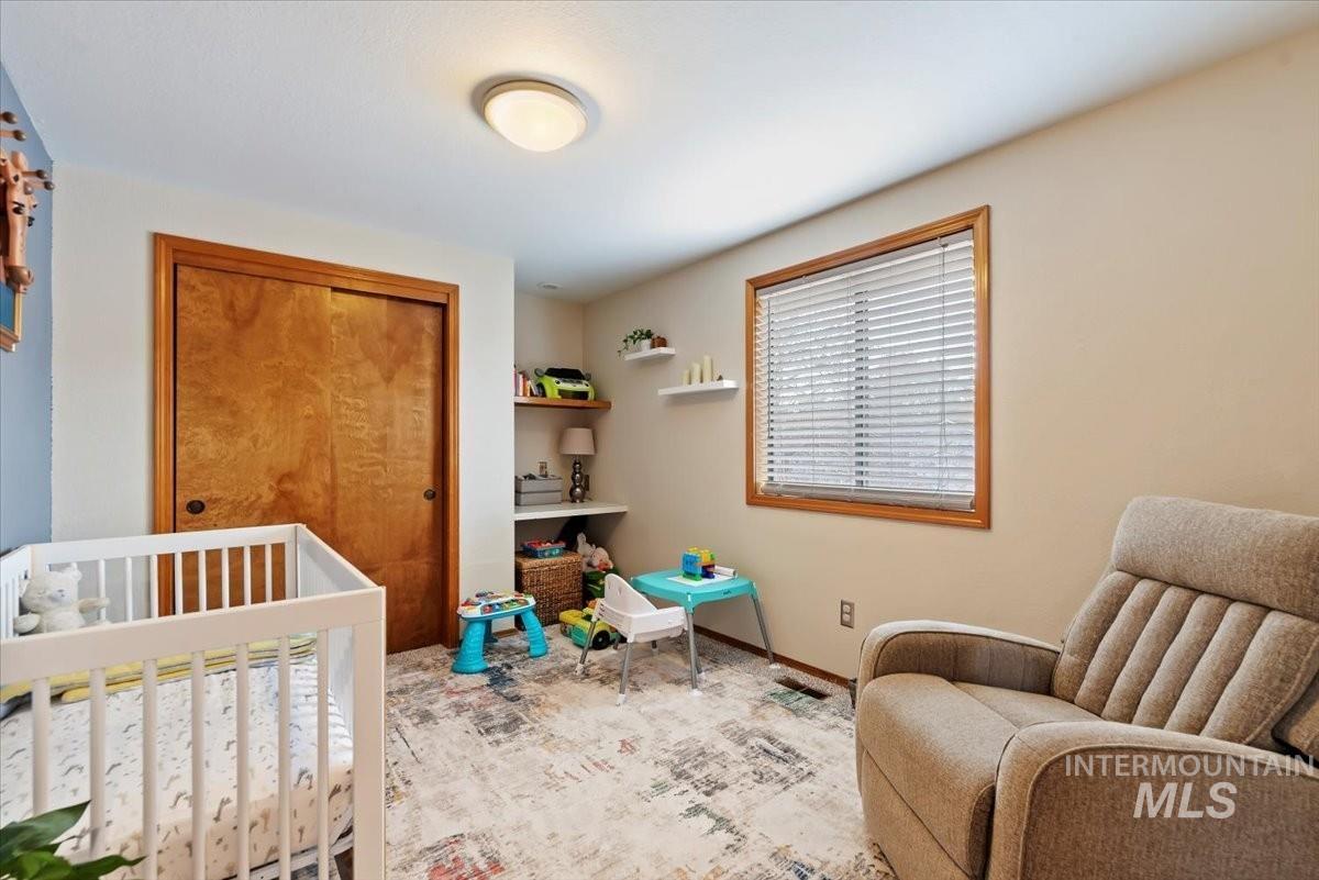 Carpeted bedroom with a closet and a crib