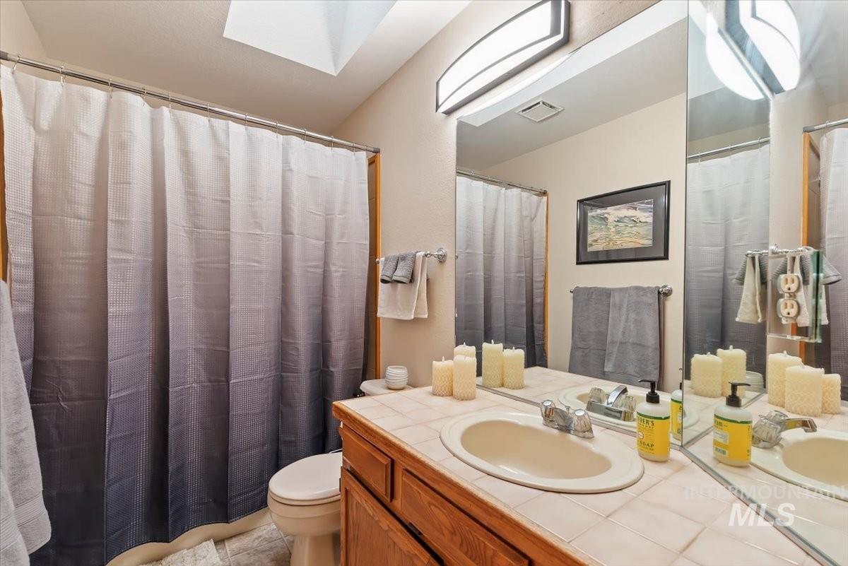 Bathroom with a shower with shower curtain, vanity, and a skylight