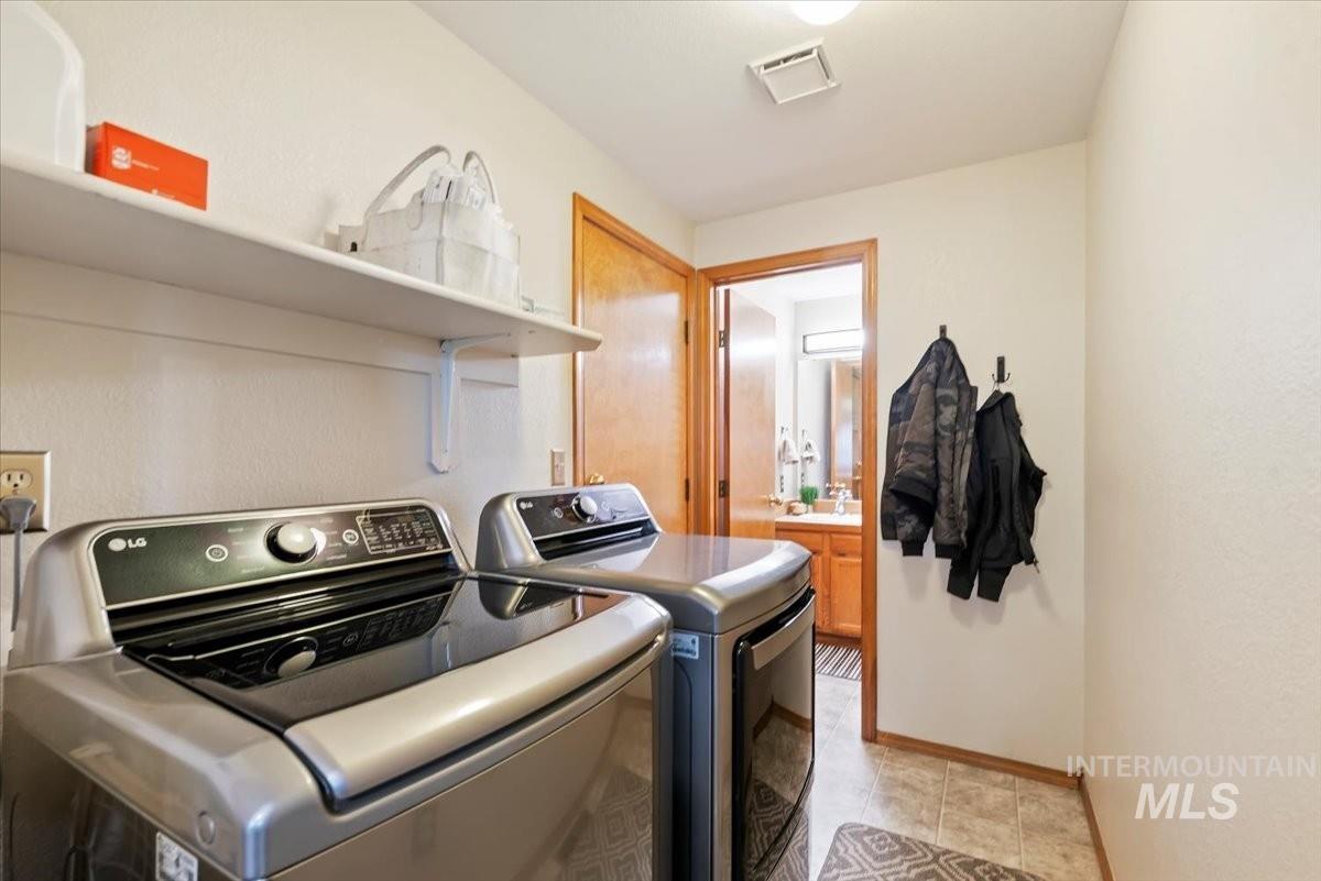 Laundry room featuring independent washer and dryer and light tile patterned floors