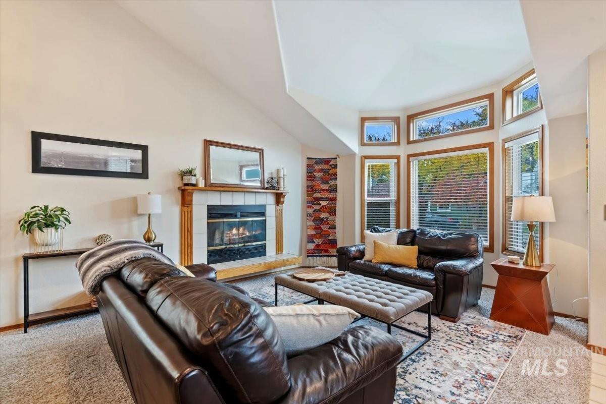 Living room with light carpet, a fireplace, and high vaulted ceiling