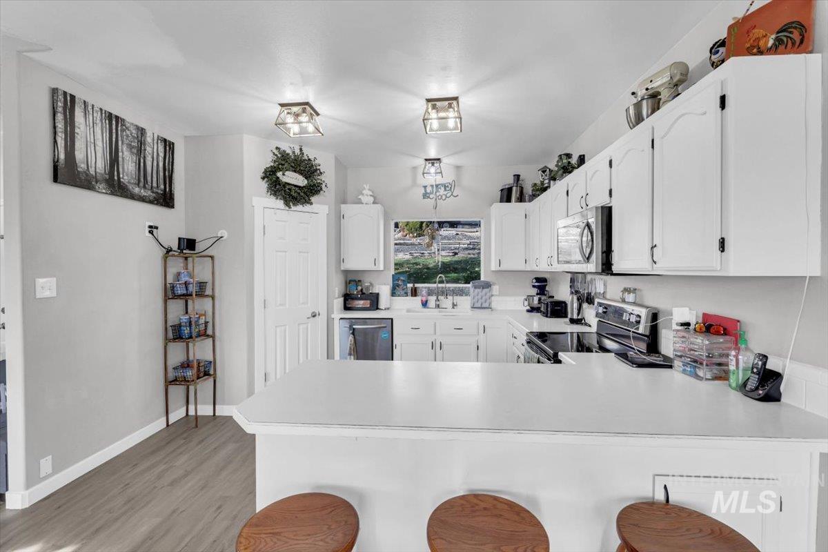 Kitchen featuring a kitchen bar, light countertops, and white cabinetry