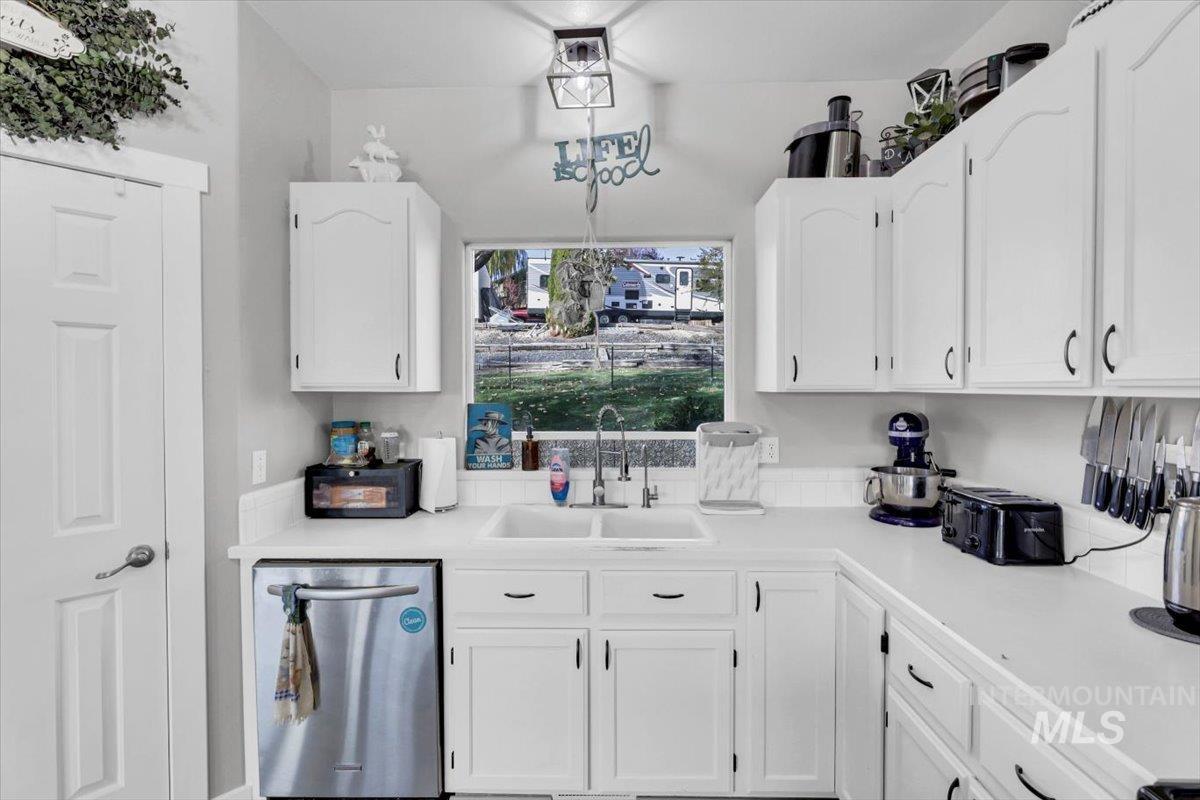 Kitchen with light countertops, white cabinets, and dishwasher