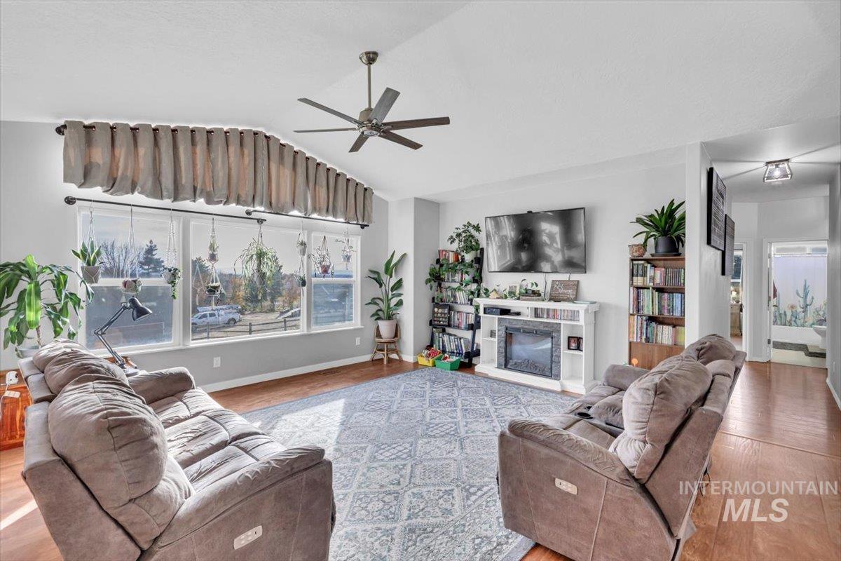 Living area featuring vaulted ceiling, plenty of natural light, light wood-type flooring, and a ceiling fan