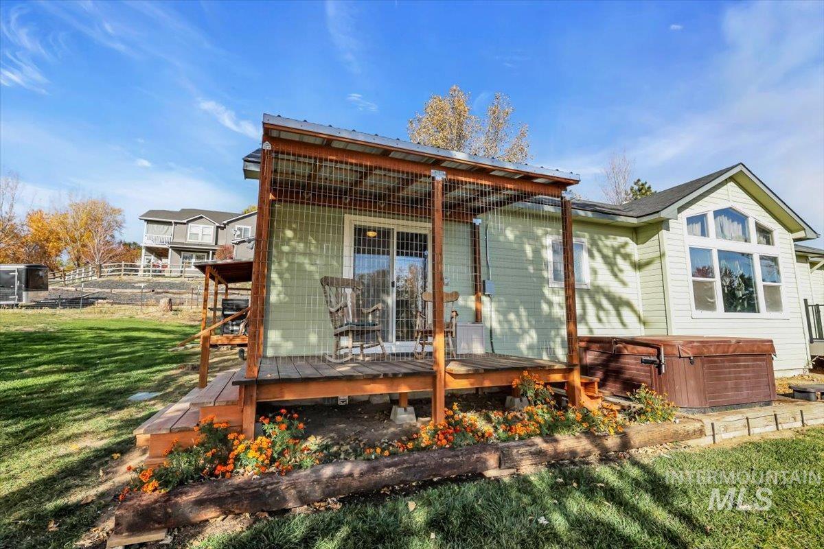 Back of house featuring a deck and a hot tub