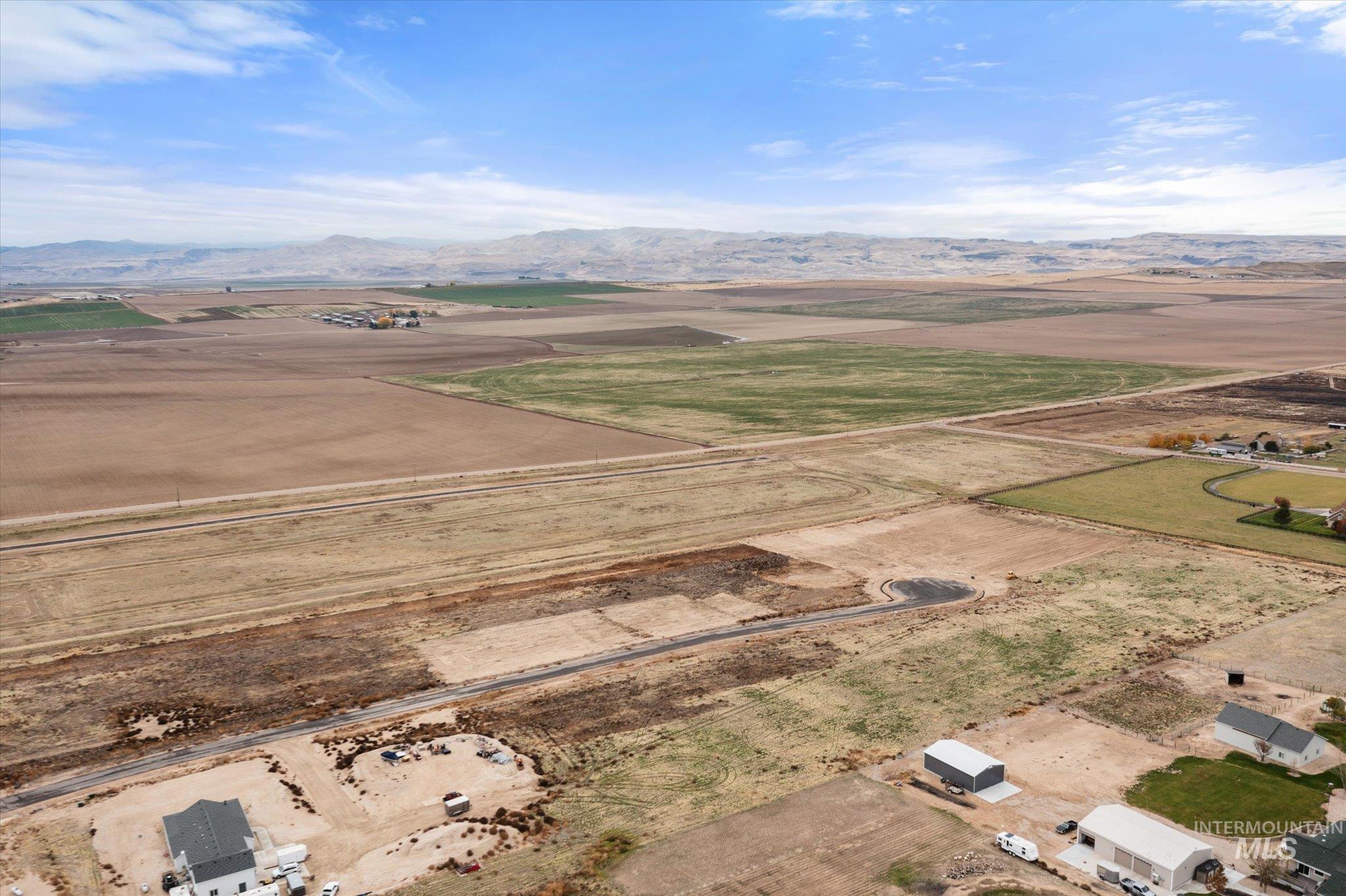 Aerial view of property and surrounding area featuring rural landscape and a mountain backdrop