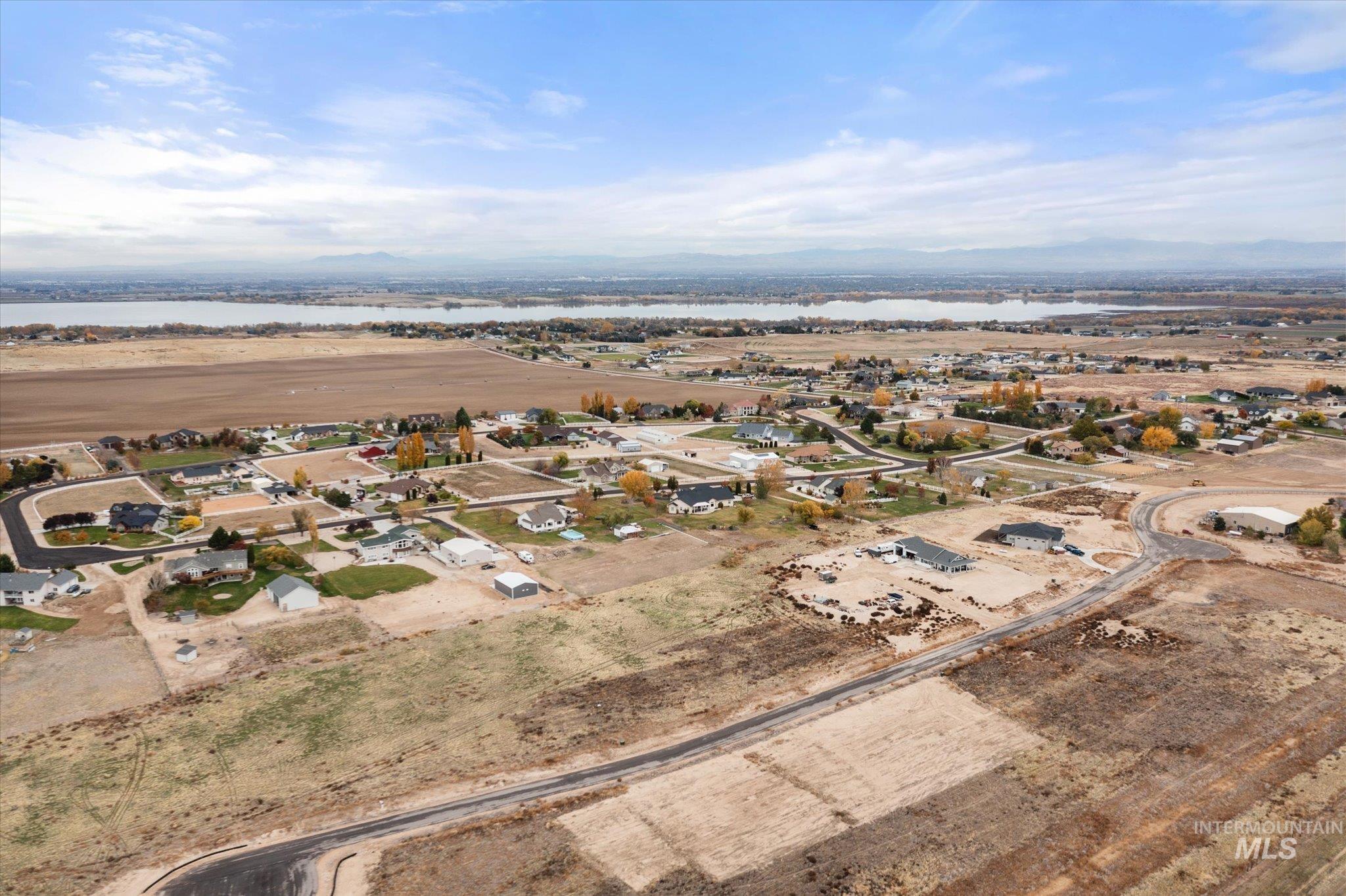 Aerial view of property and surrounding area featuring nearby suburban area and a nearby body of water