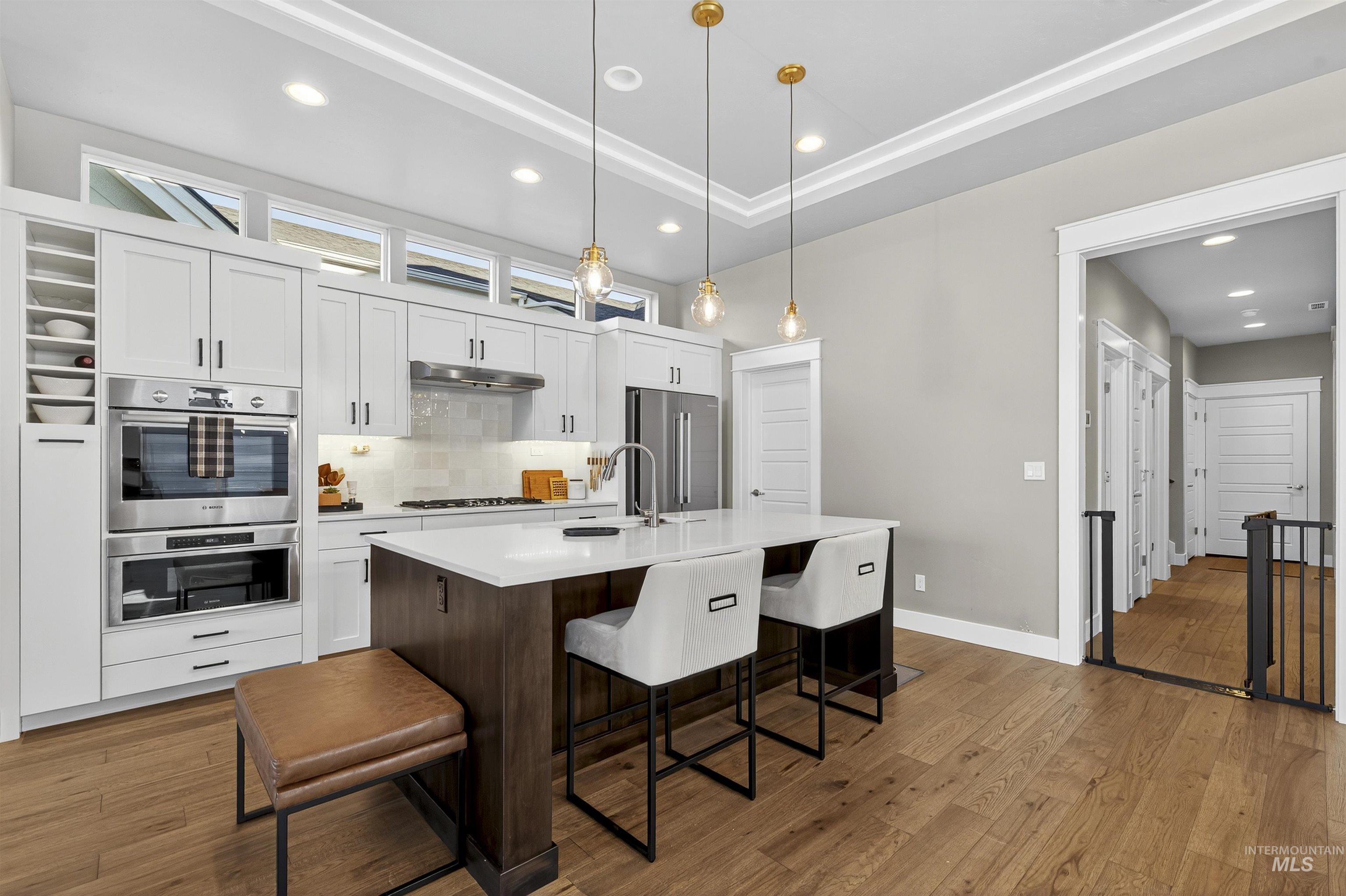 Kitchen with white cabinetry, a kitchen breakfast bar, decorative backsplash, a center island with sink, and stainless steel appliances