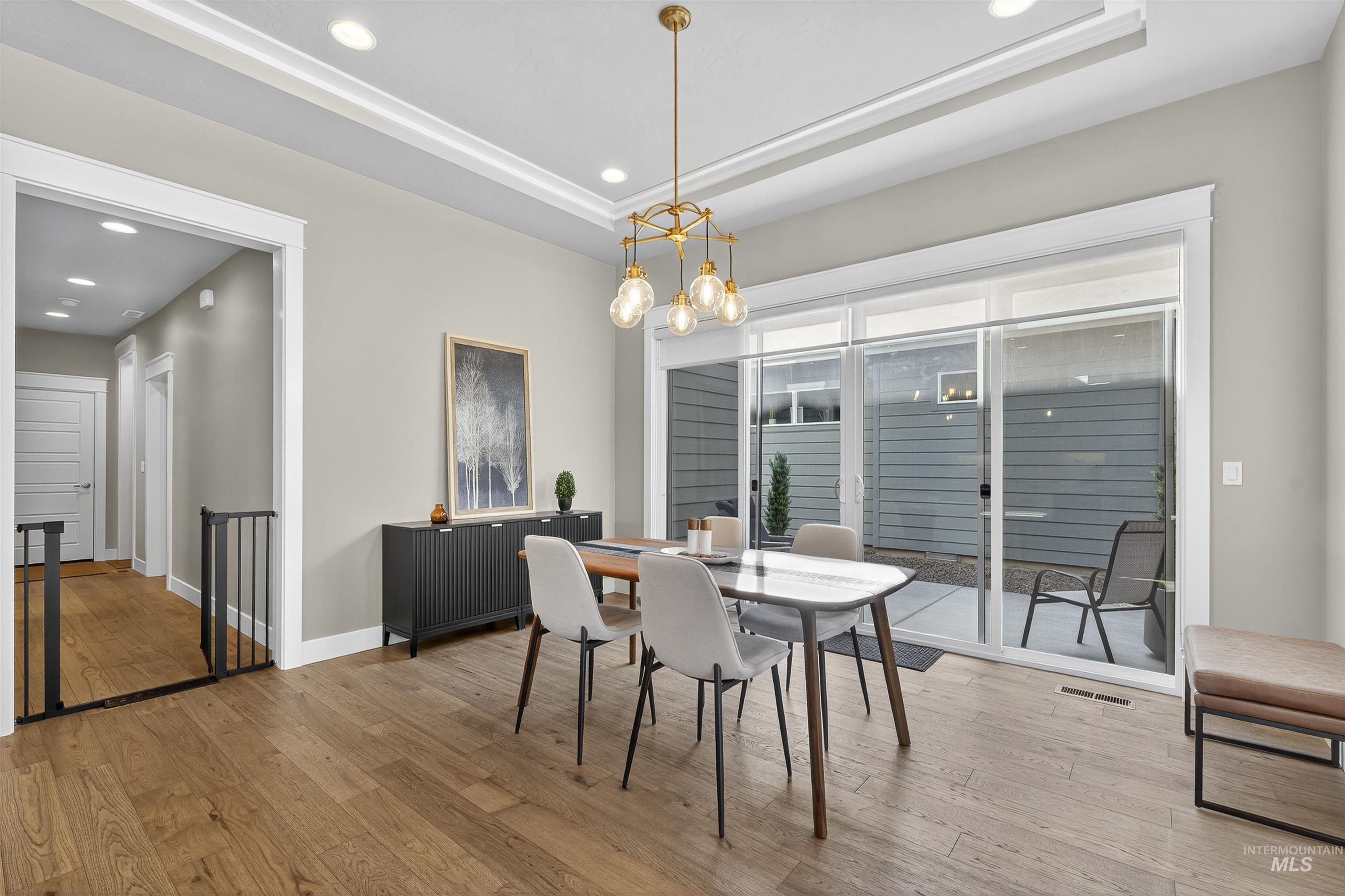 Dining space featuring a tray ceiling, light wood finished floors, recessed lighting, and a chandelier