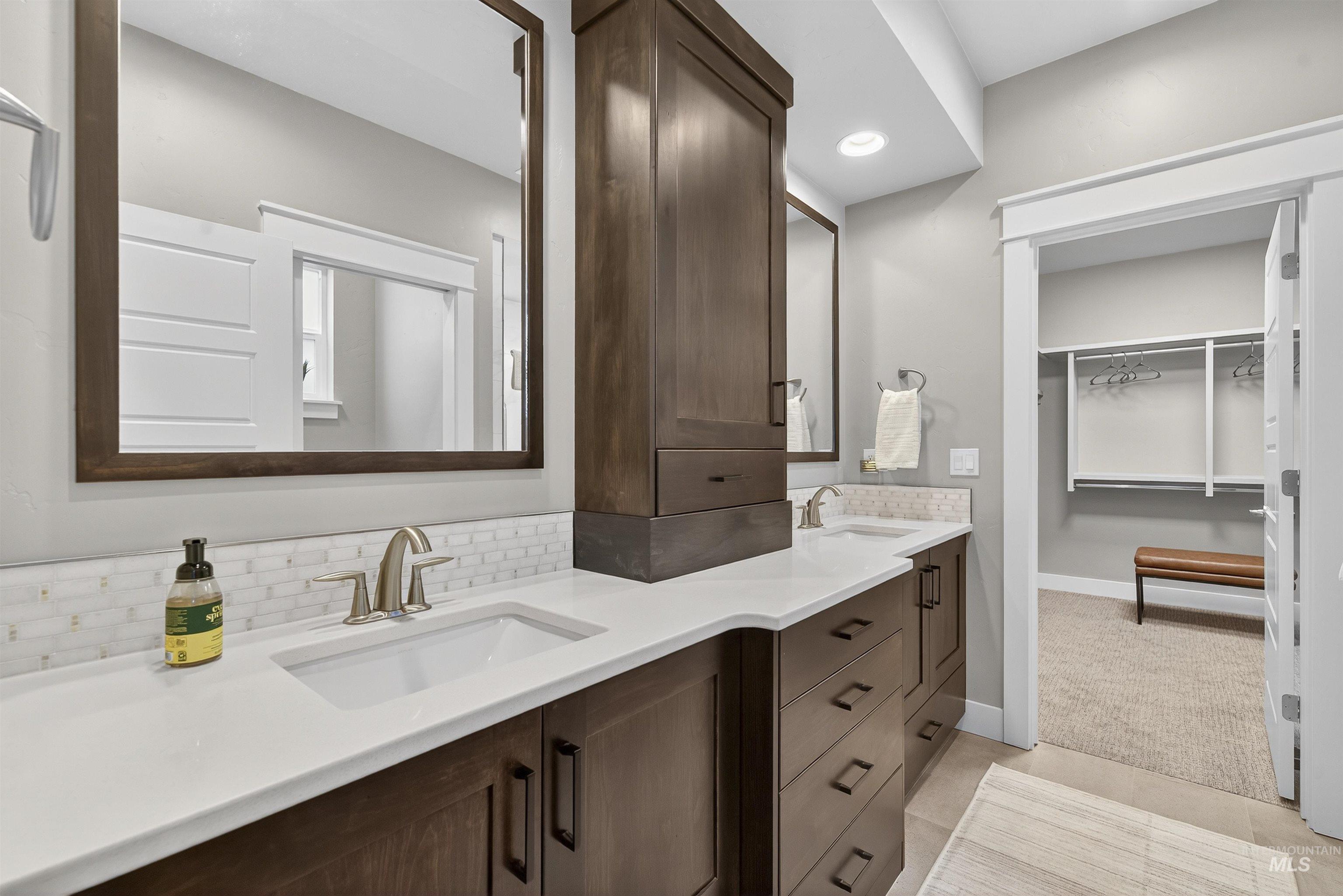 Bathroom featuring double vanity, recessed lighting, tasteful backsplash, a walk in closet, and light tile patterned flooring