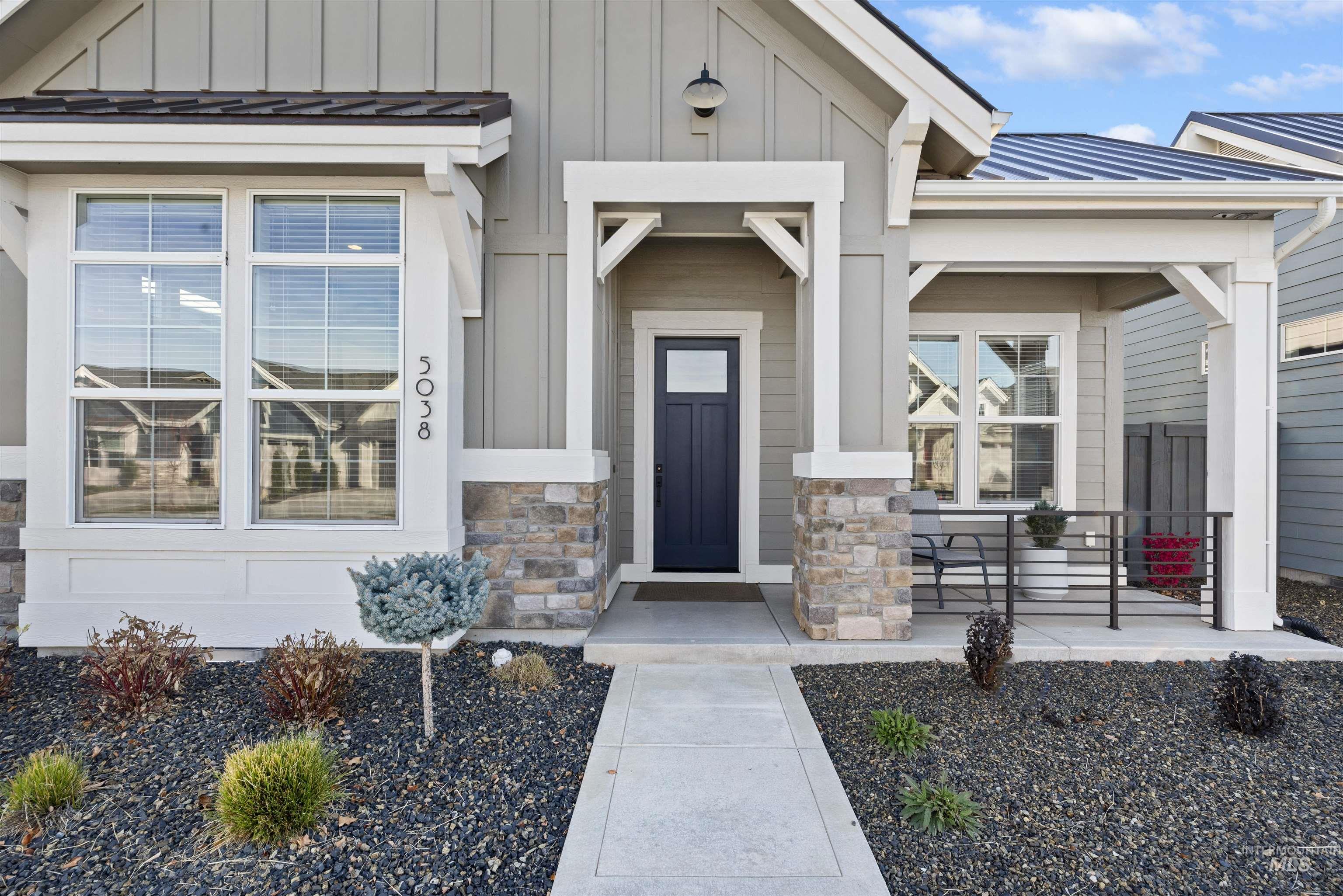 Entrance to property featuring a standing seam roof, board and batten siding, a metal roof, covered porch, and stone siding