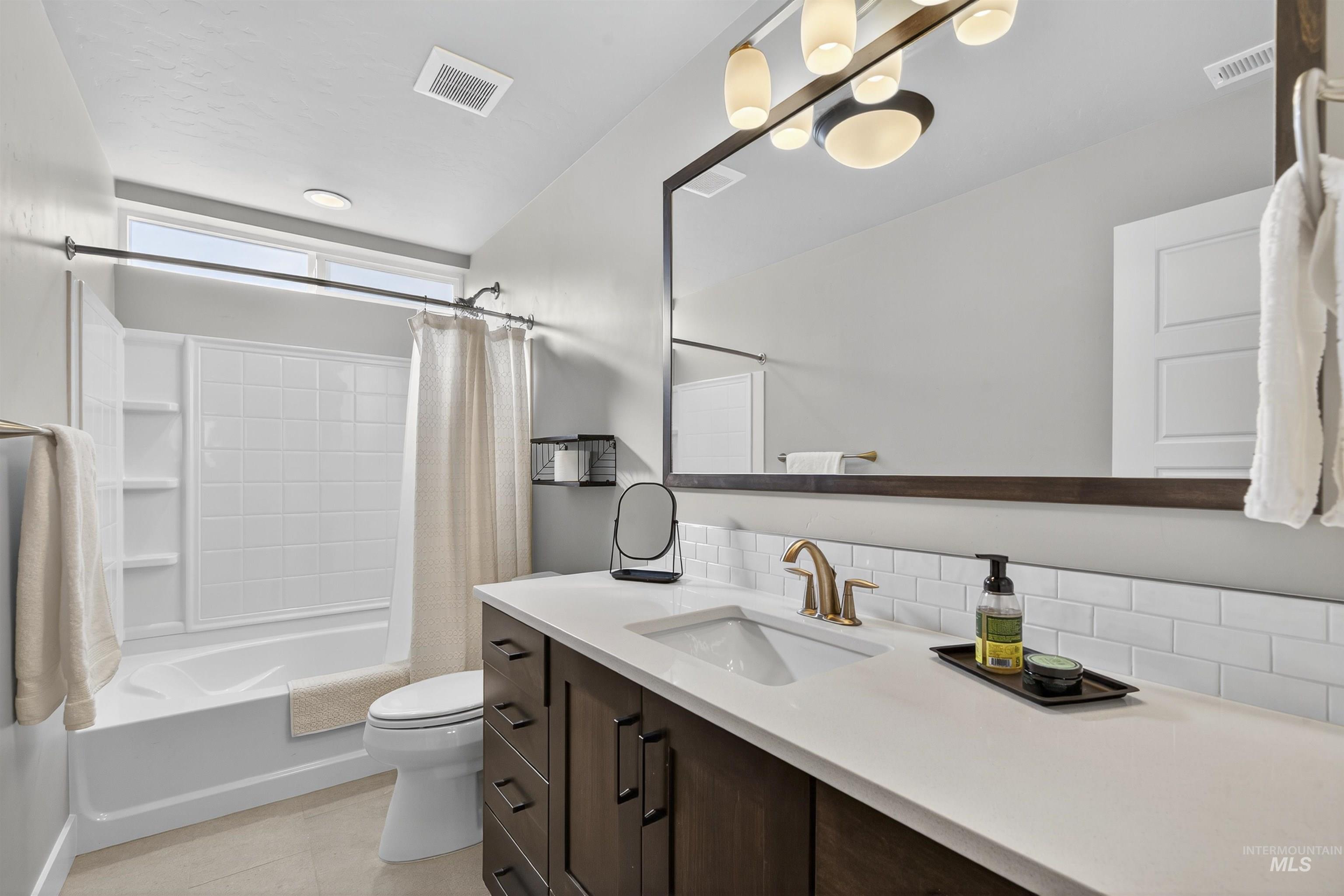 Bathroom with shower / bath combo, vanity, and light tile patterned floors