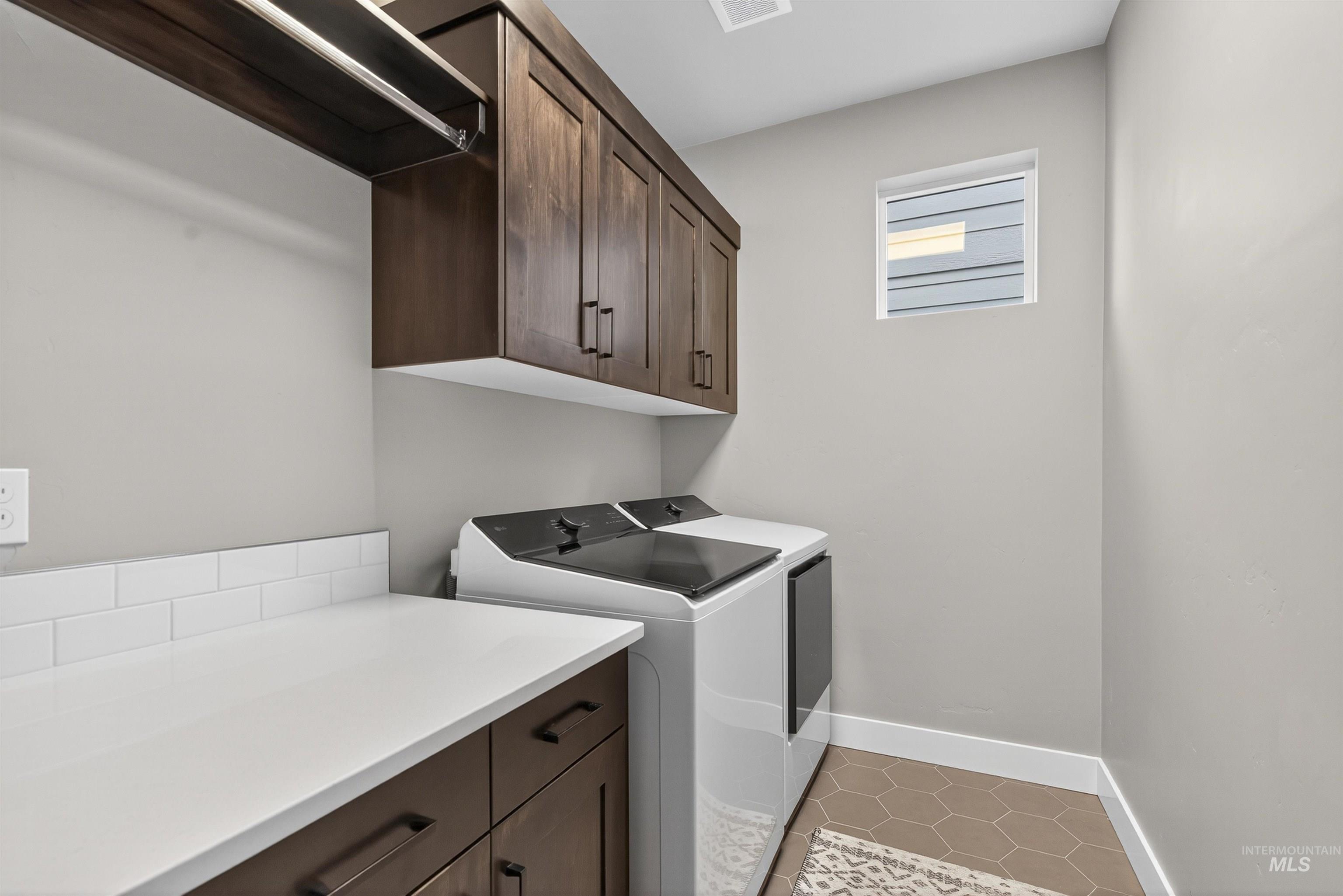 Washroom featuring light tile patterned flooring, cabinet space, and washer and dryer