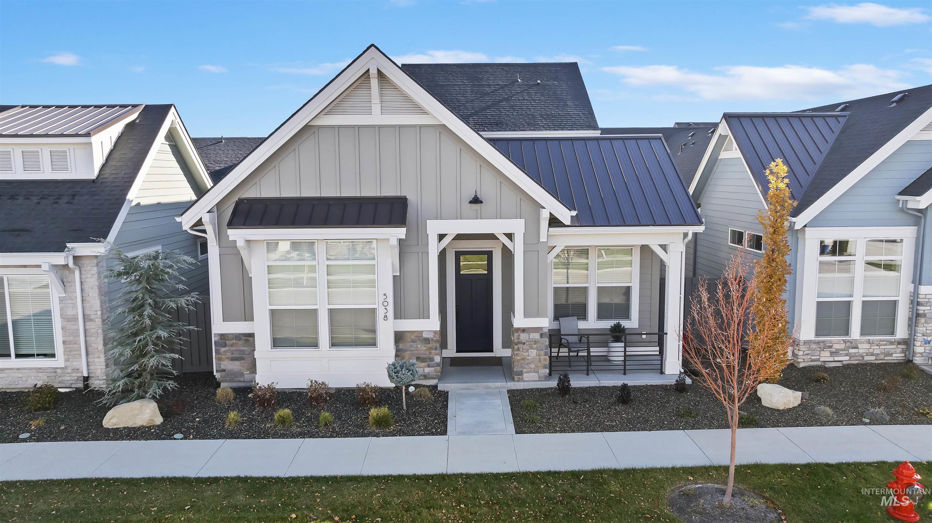 View of front facade with stone siding, board and batten siding, a standing seam roof, and a metal roof