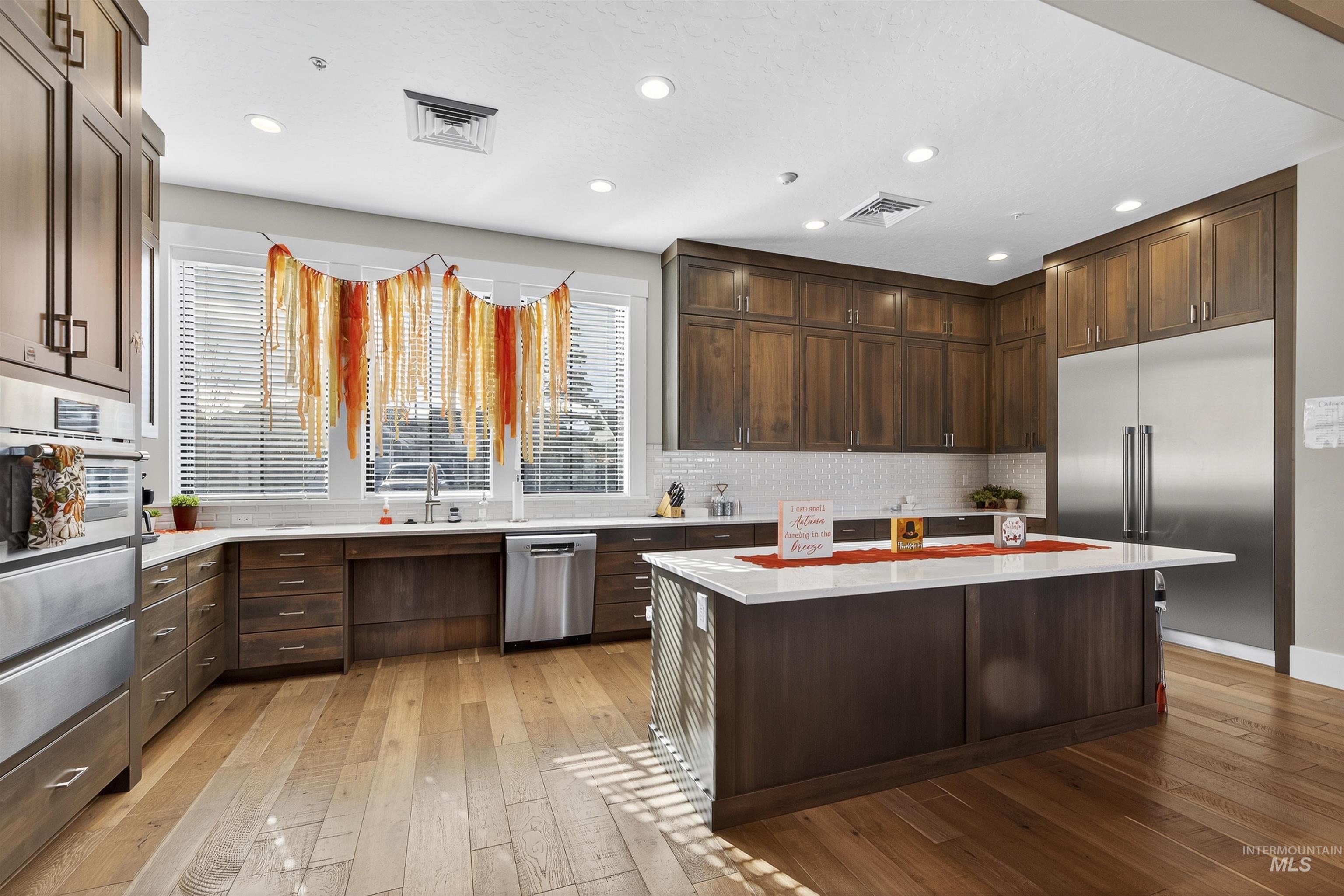 Kitchen featuring dark brown cabinetry, light wood-style floors, appliances with stainless steel finishes, recessed lighting, and a kitchen island