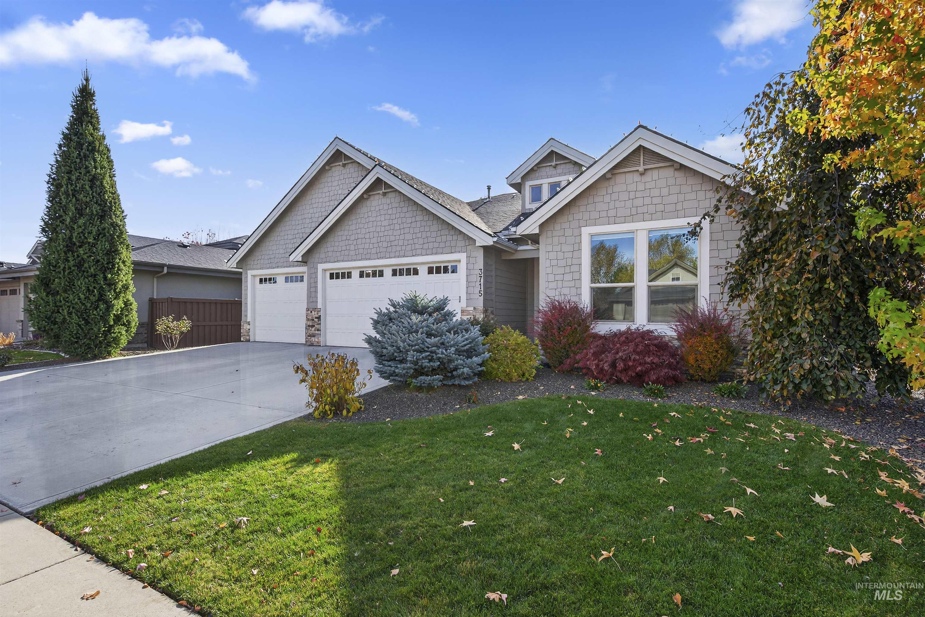 View of front facade featuring concrete driveway, an attached garage, stone siding, and a front yard