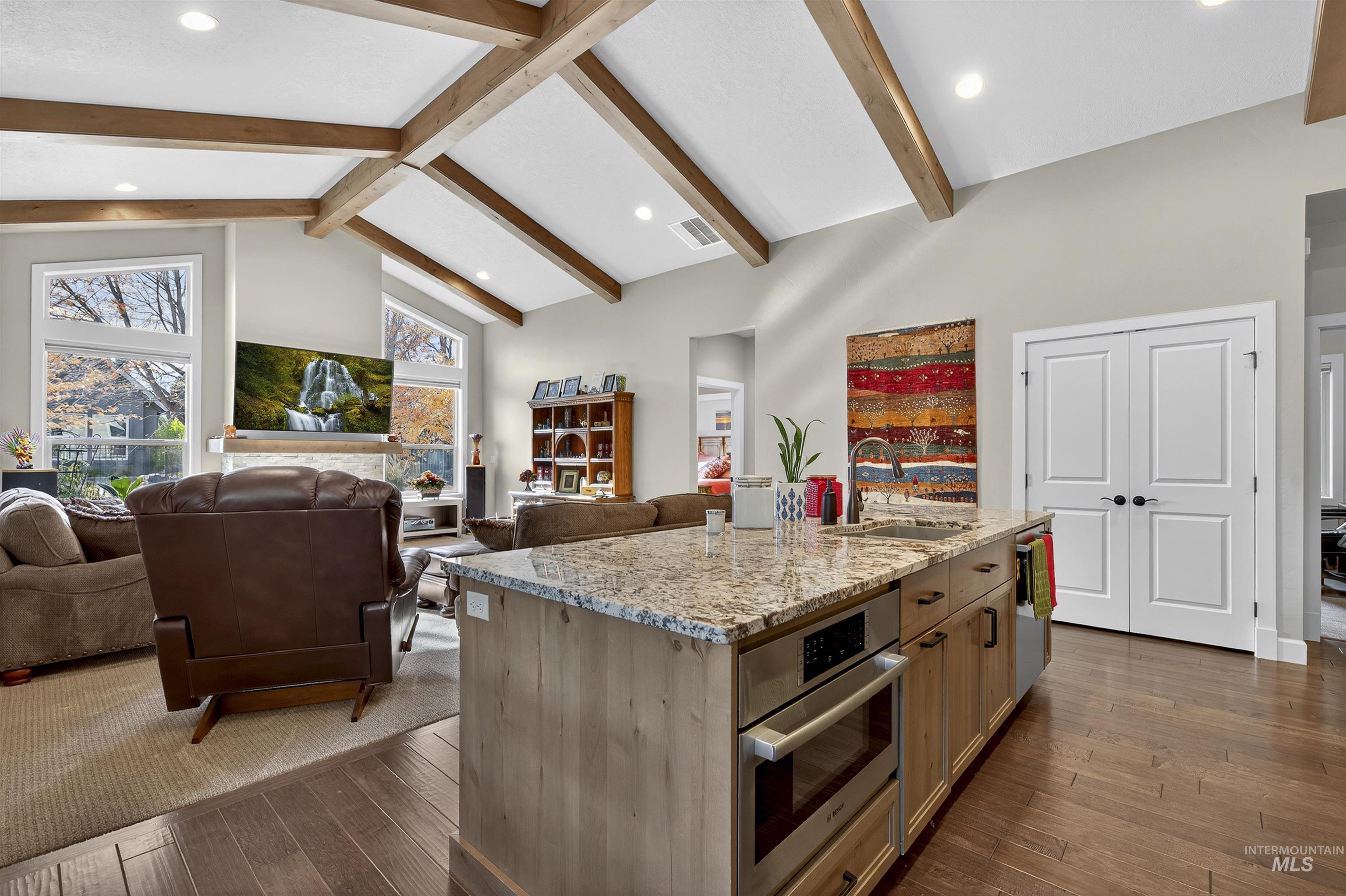 Kitchen featuring light stone counters, open floor plan, high vaulted ceiling, stainless steel appliances, and recessed lighting