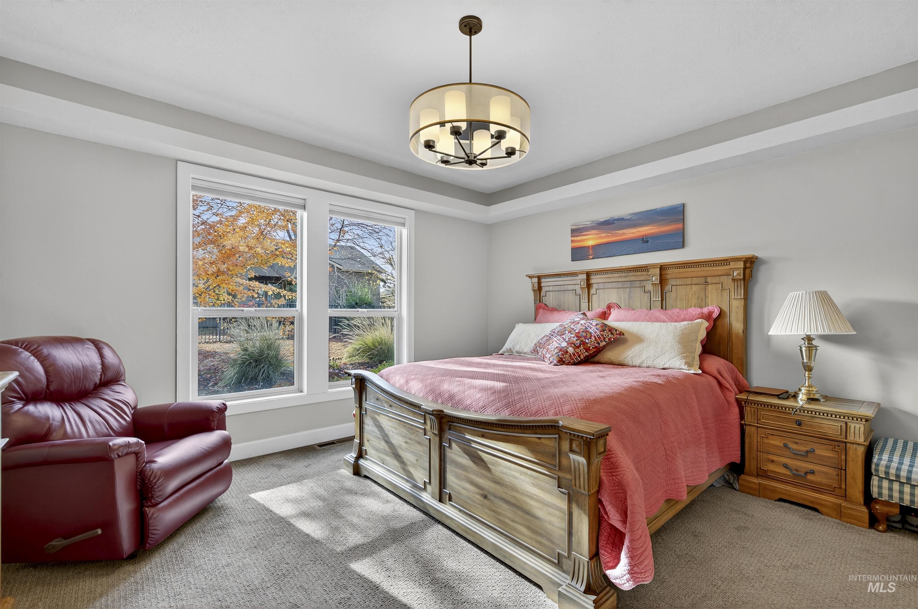 Carpeted bedroom with a chandelier and baseboards